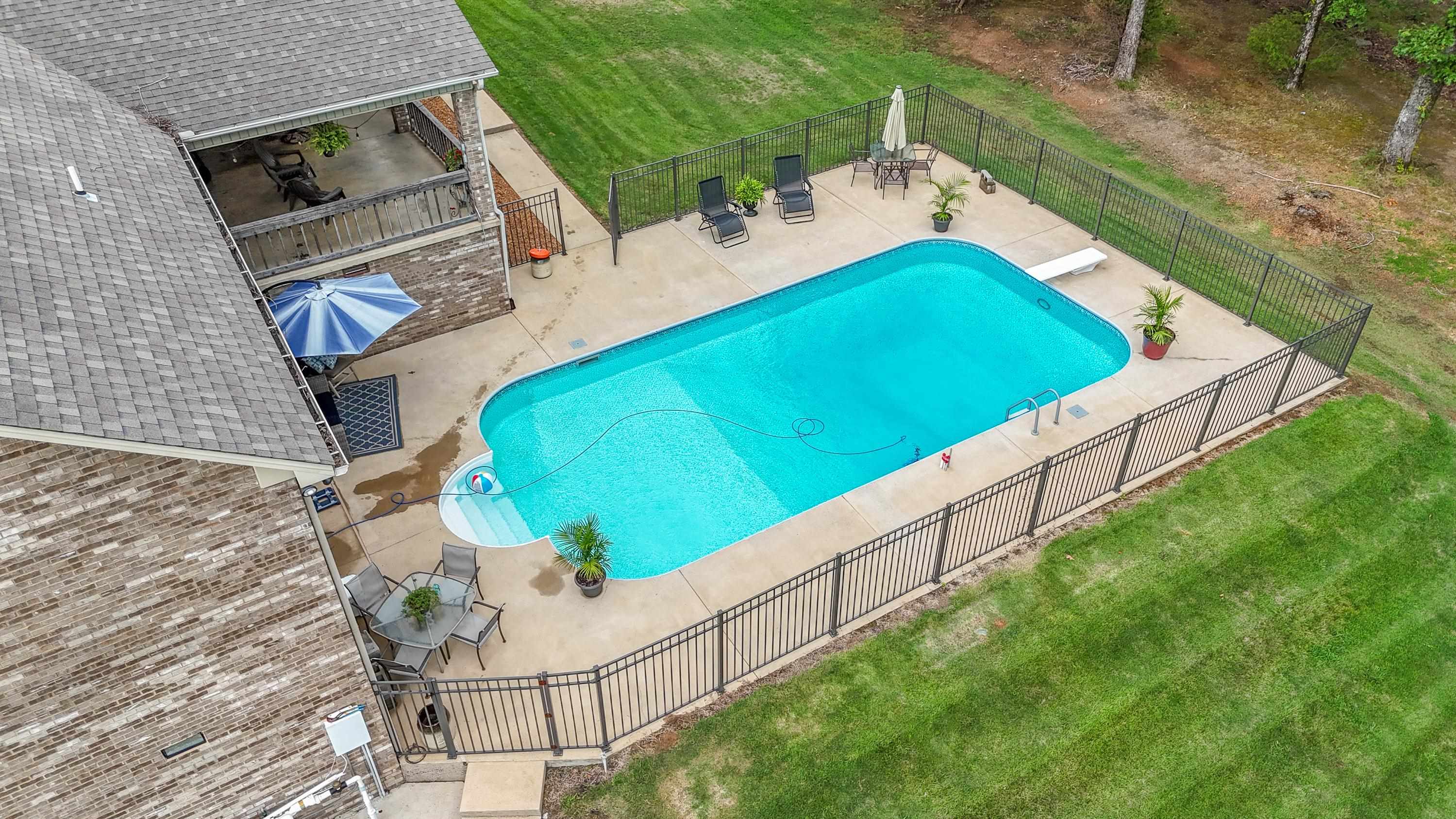 View of swimming pool featuring a diving board, a patio area, and a lawn