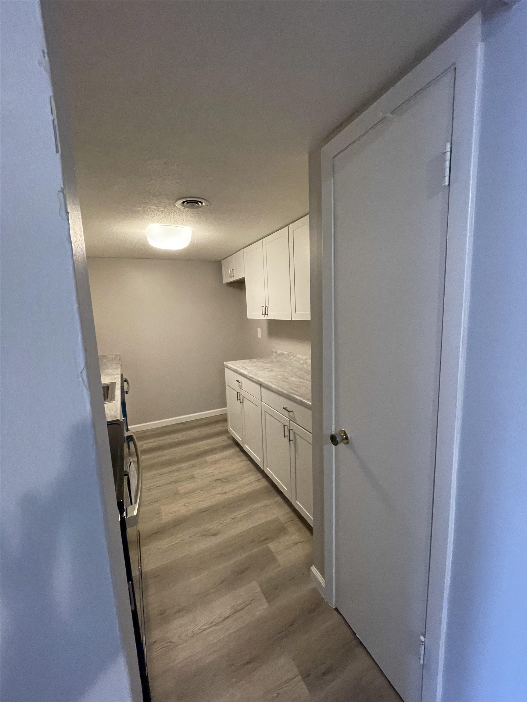 Kitchen with light hardwood / wood-style flooring, a textured ceiling, and white cabinets