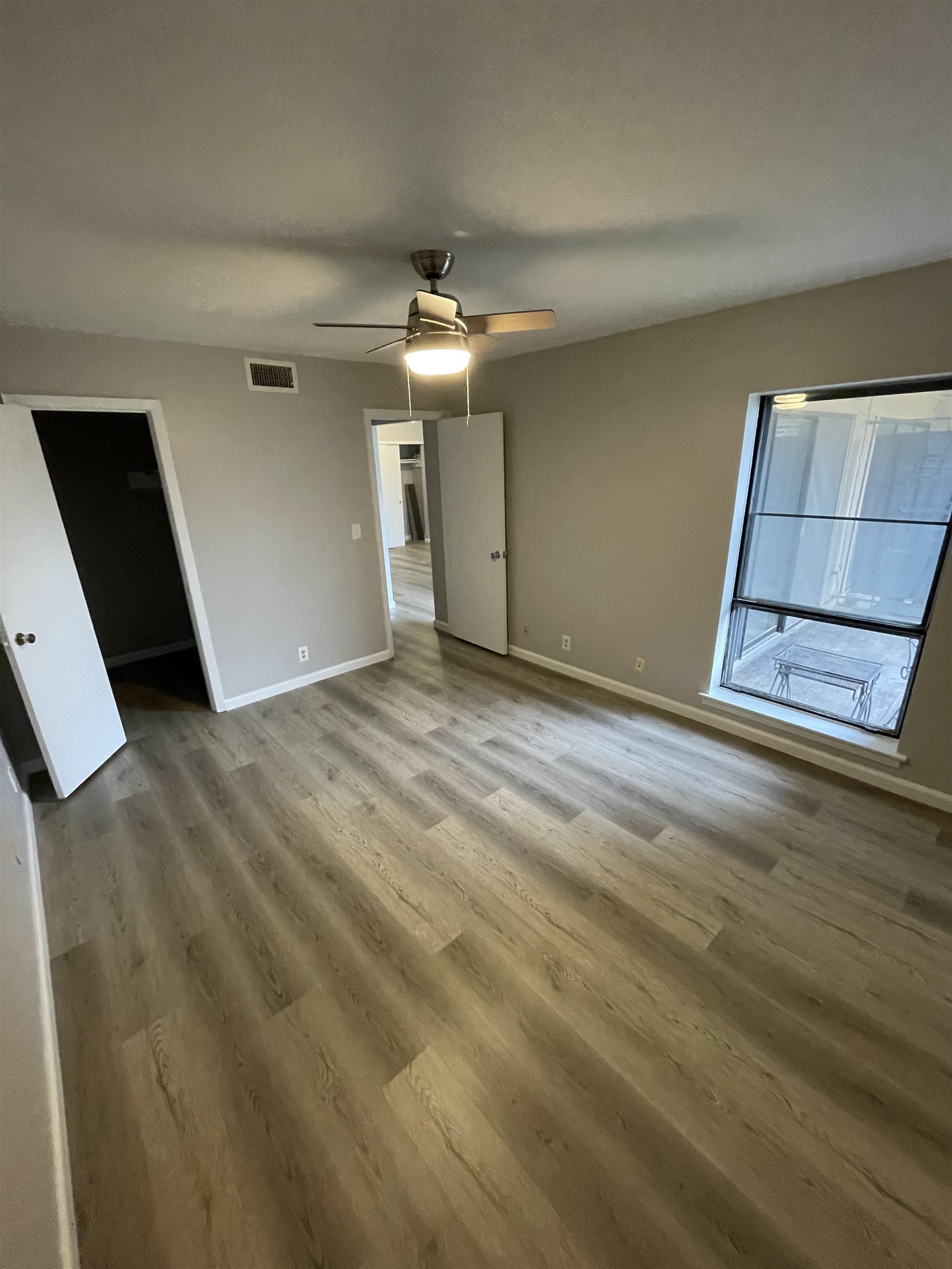 Unfurnished bedroom featuring a spacious closet, hardwood / wood-style flooring, and ceiling fan