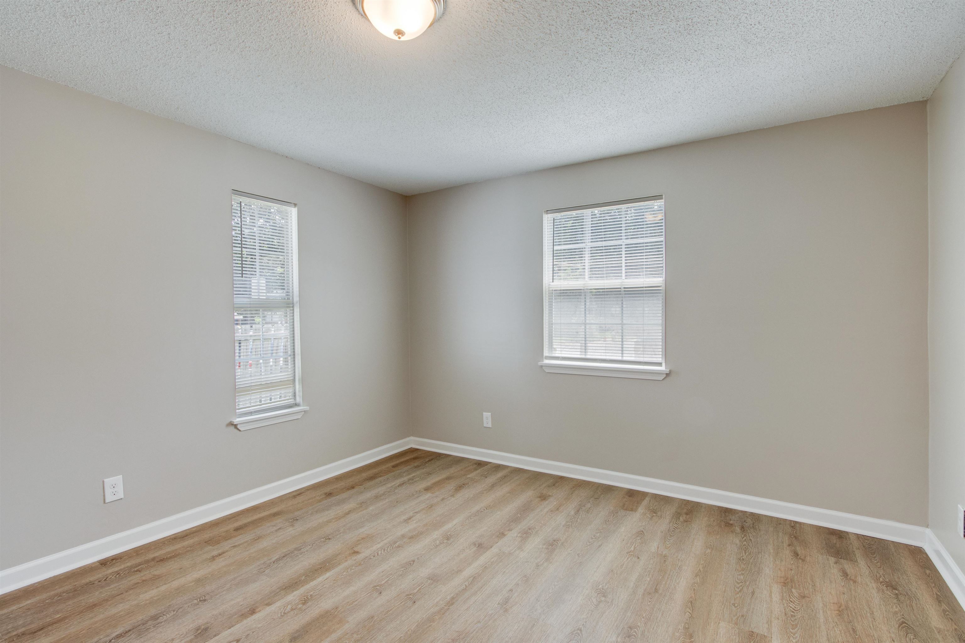 Unfurnished room featuring a textured ceiling, light hardwood / wood-style flooring, and a healthy amount of sunlight