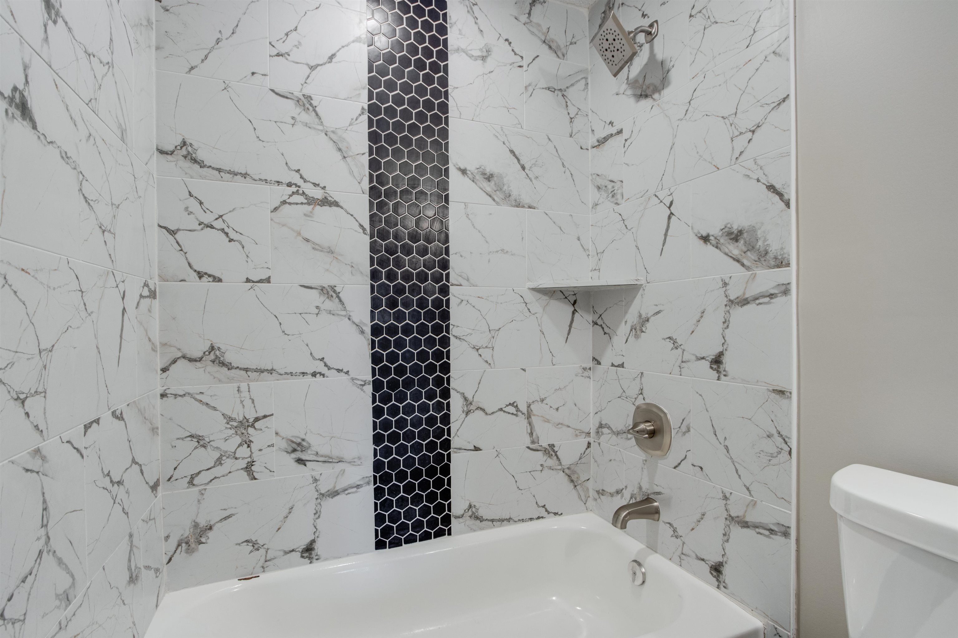 Bathroom with tiled shower / bath combo and toilet