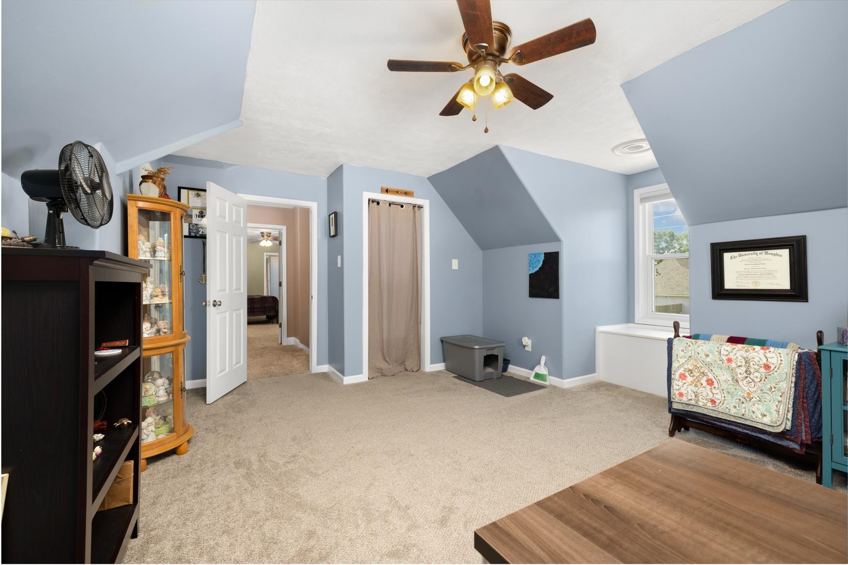 Bedroom with light carpet, ceiling fan, and vaulted ceiling