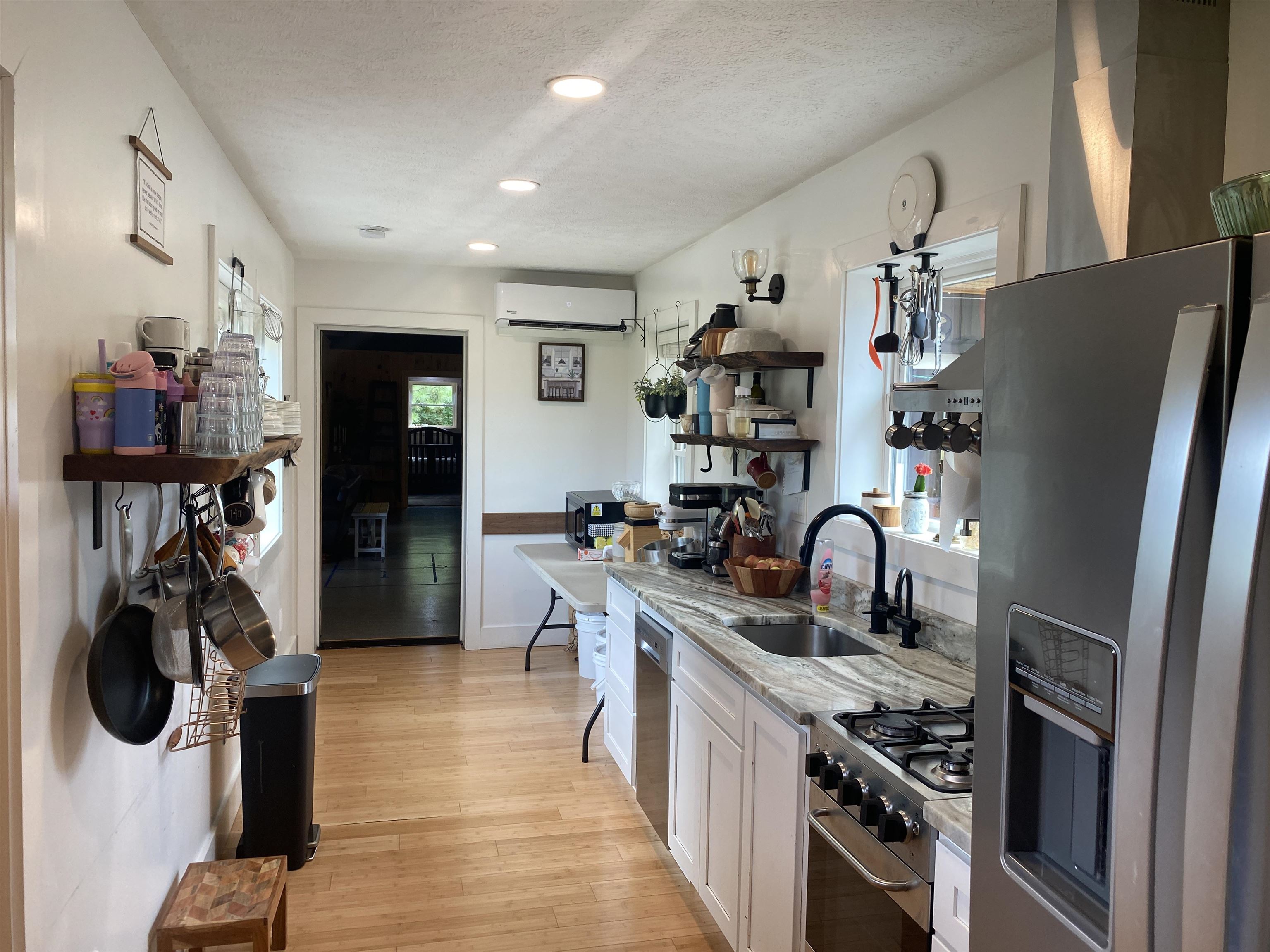 Kitchen featuring white cabinetry, light hardwood / wood-style flooring, appliances with stainless steel finishes, a wall unit AC, and sink