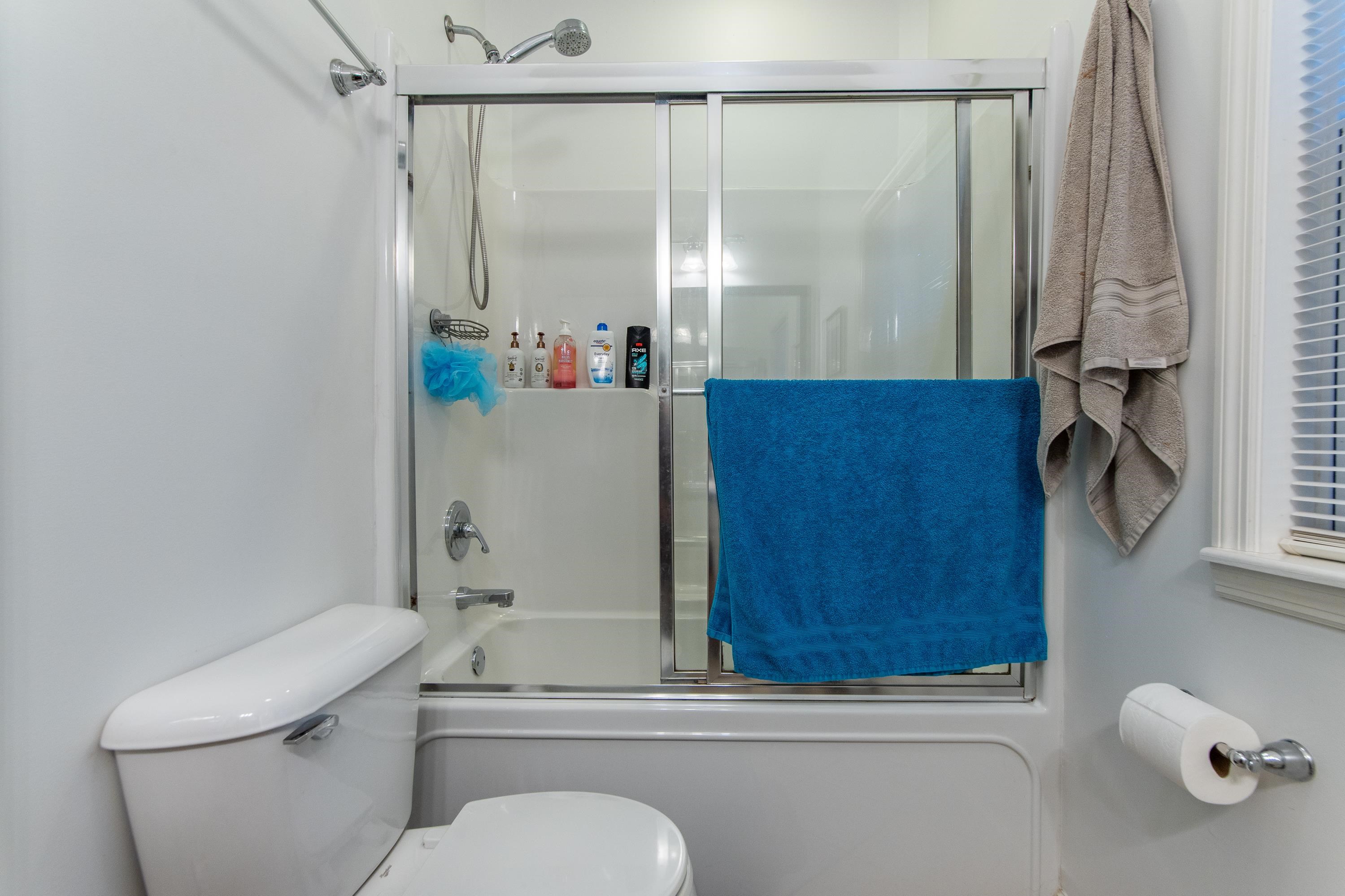 Bathroom featuring combined bath / shower with glass door and toilet