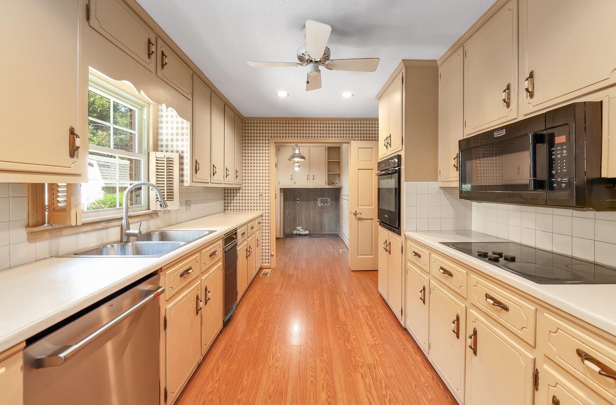 Kitchen featuring ceiling fan, light hardwood / wood-style floors, black appliances, decorative backsplash, and sink