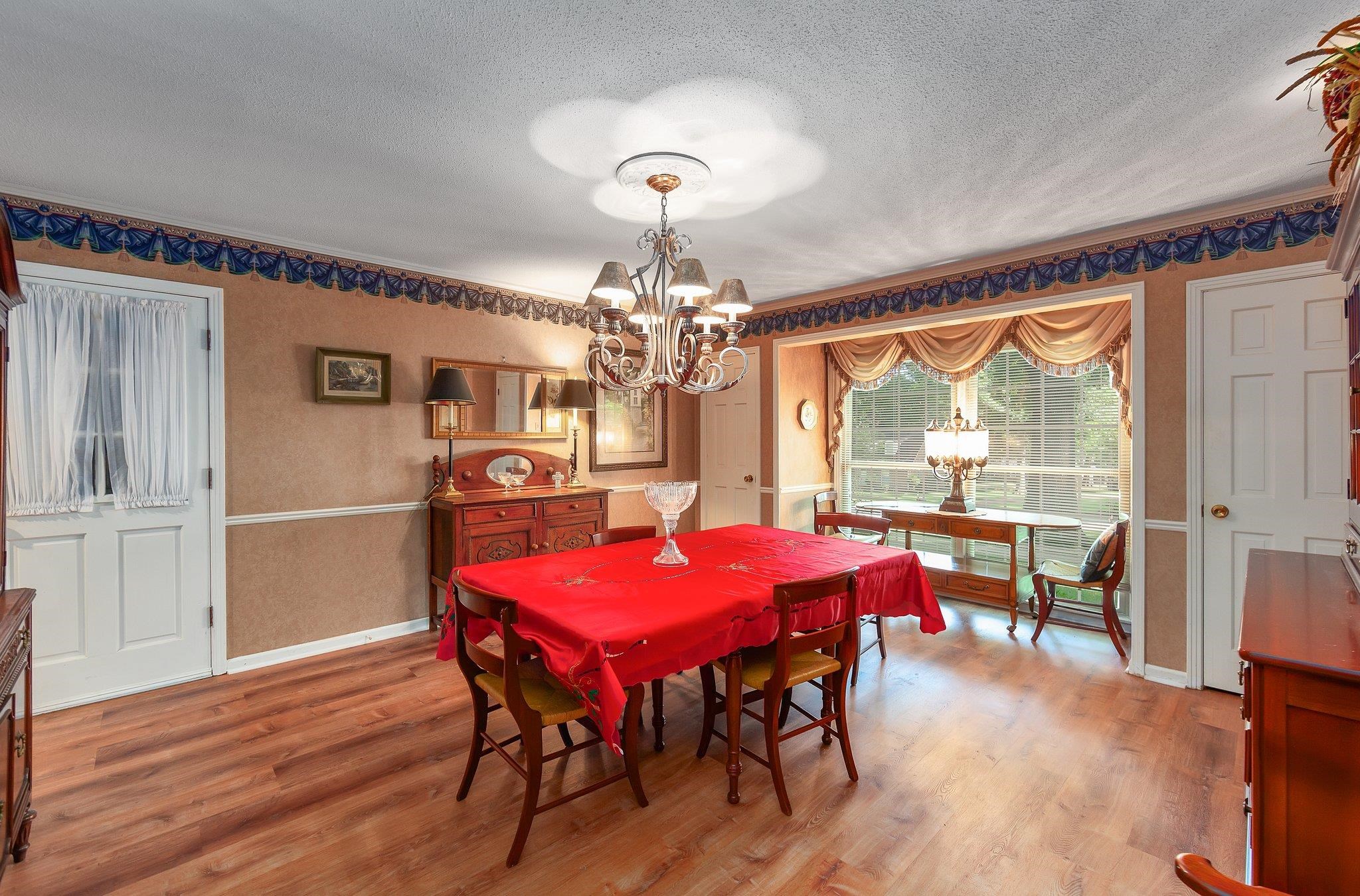 Dining room featuring an inviting chandelier, a textured ceiling, and light wood-type flooring