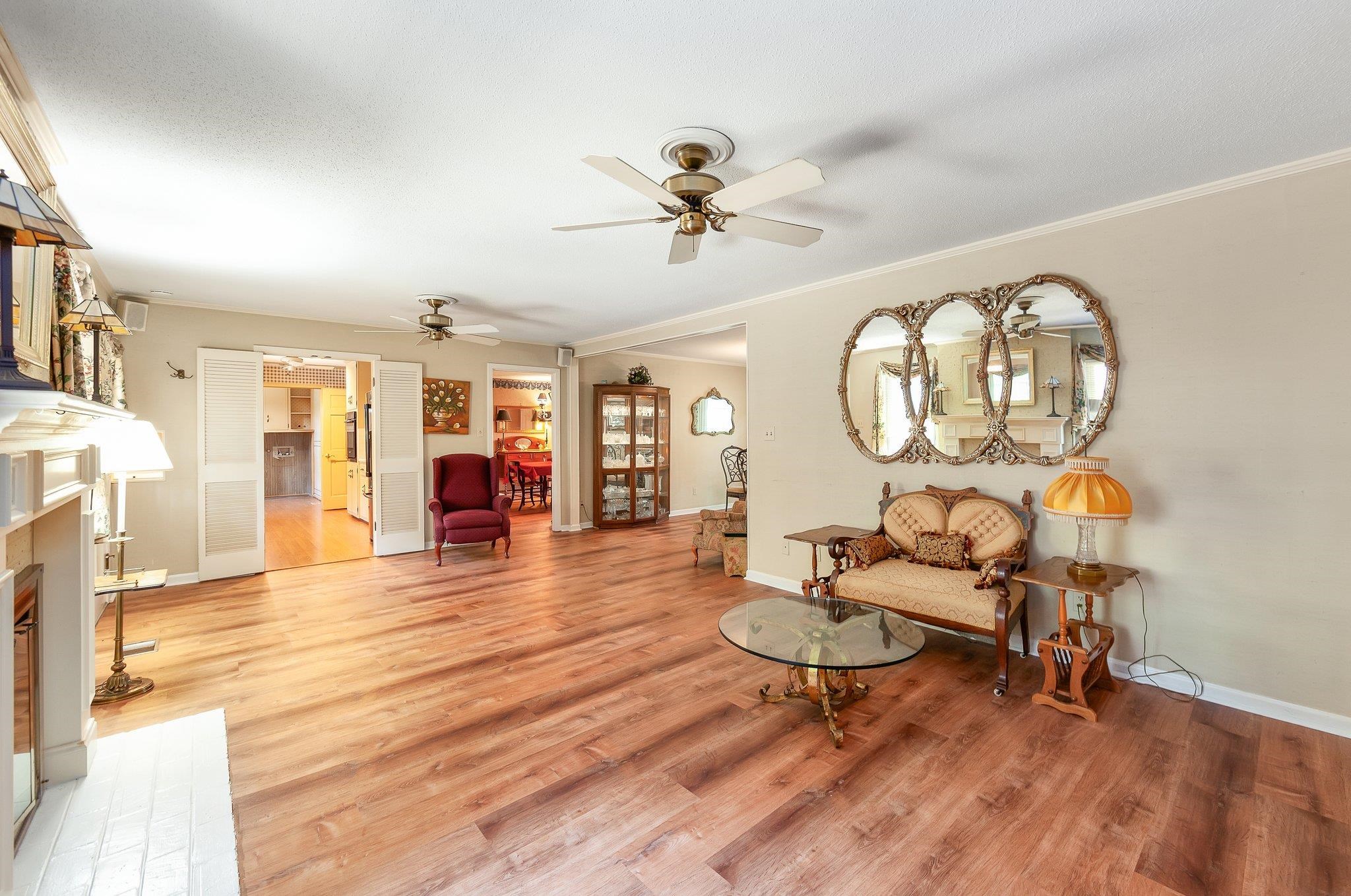 Living room featuring ornamental molding, wood-type flooring, and ceiling fan