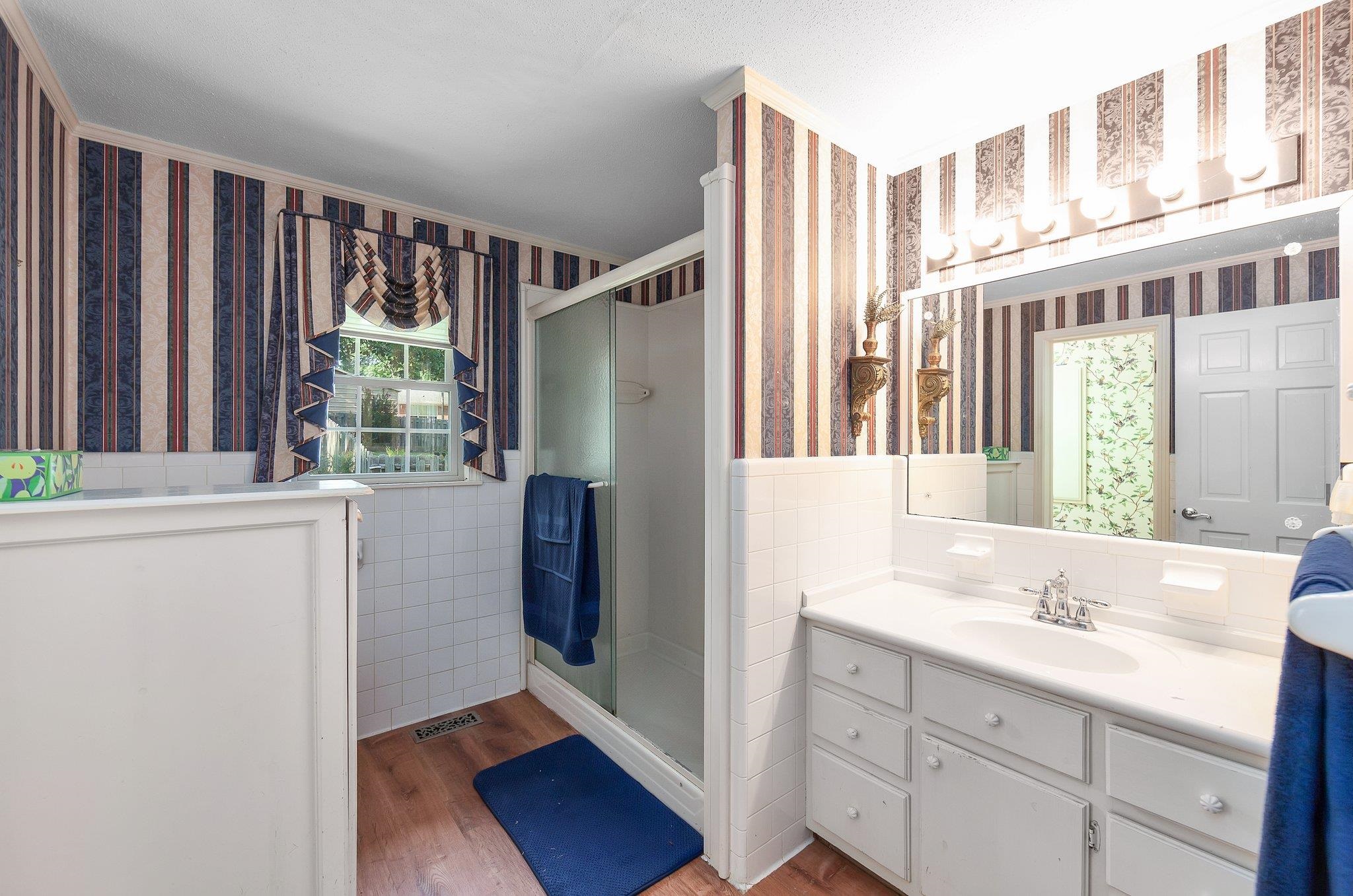 Bathroom featuring vanity, walk in shower, tile walls, and hardwood / wood-style flooring