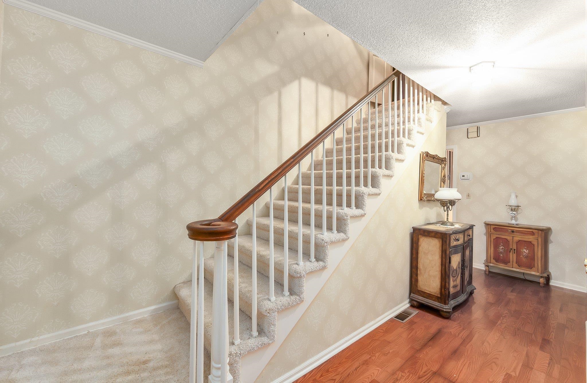 Stairs with crown molding, dark hardwood / wood-style flooring, and a textured ceiling