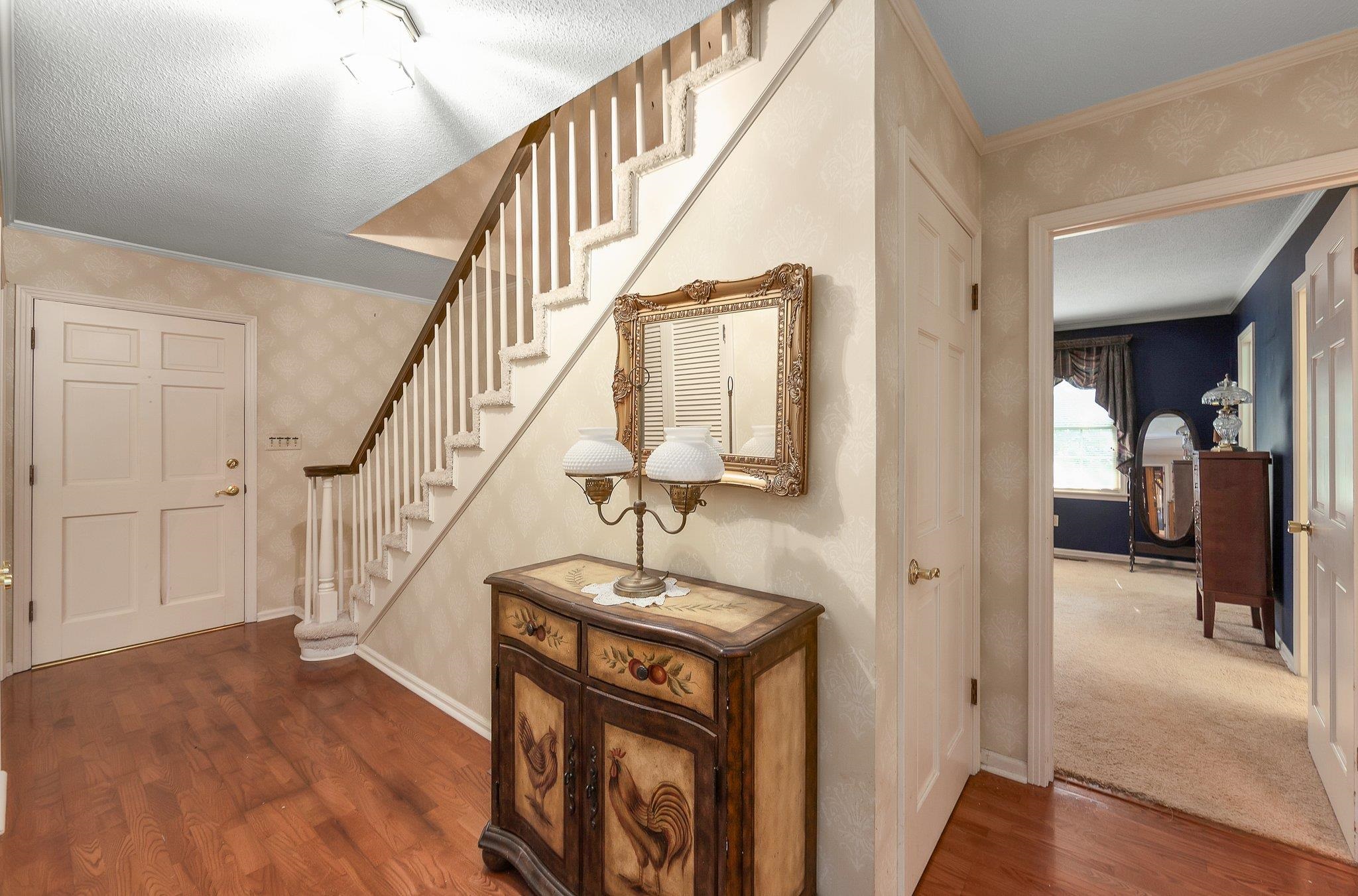 Hall featuring ornamental molding, carpet, and a textured ceiling