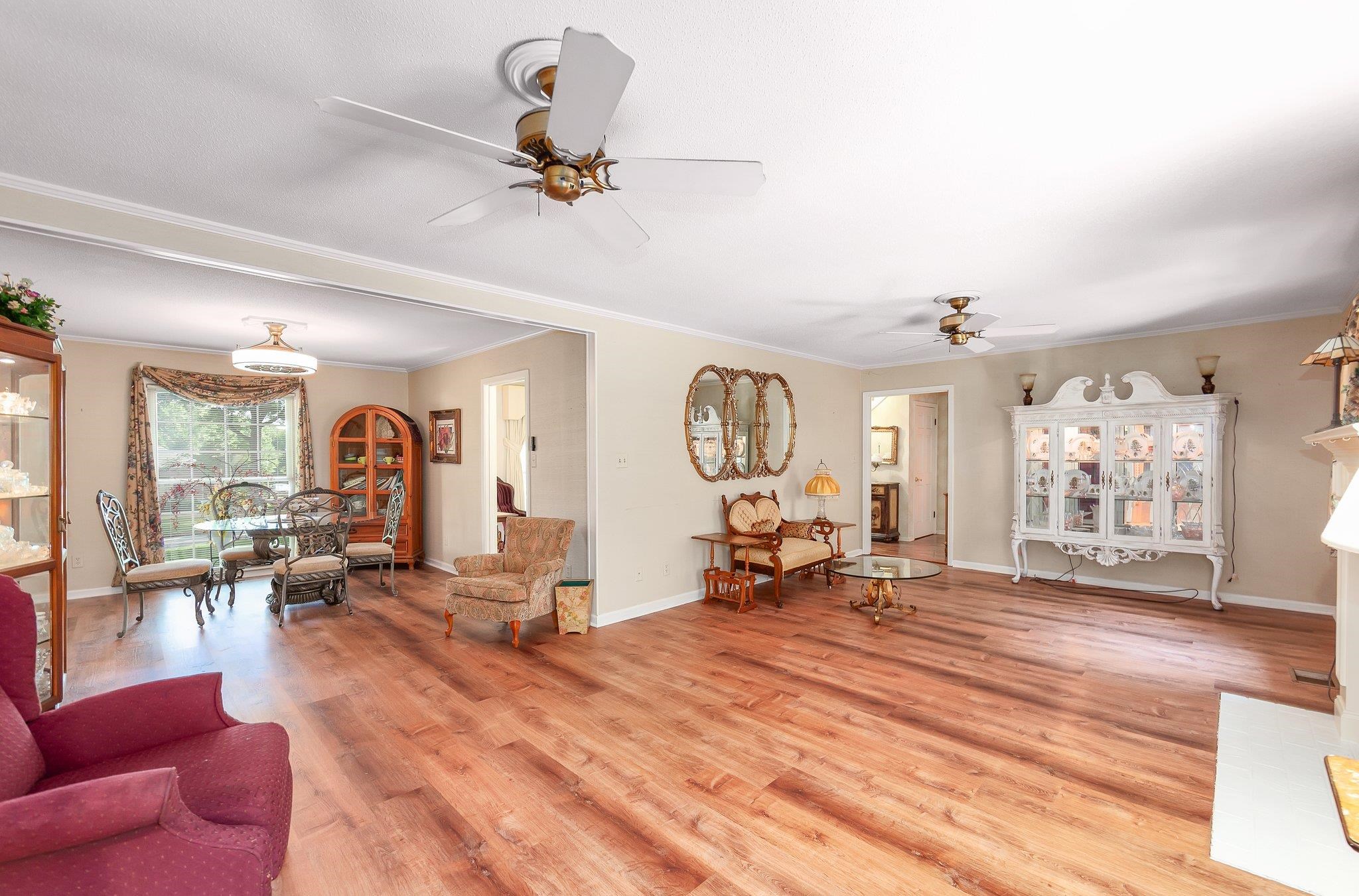 Living room featuring light wood-type flooring, ceiling fan, and ornamental molding