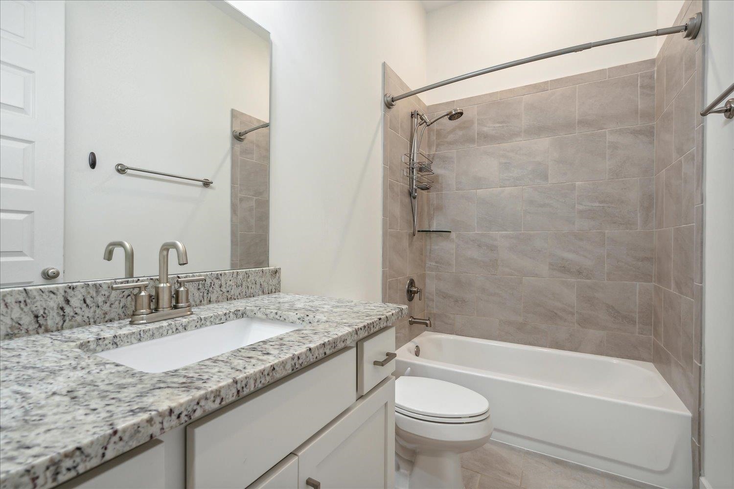 Full bathroom featuring vanity, tiled shower / bath combo, toilet, and tile patterned flooring