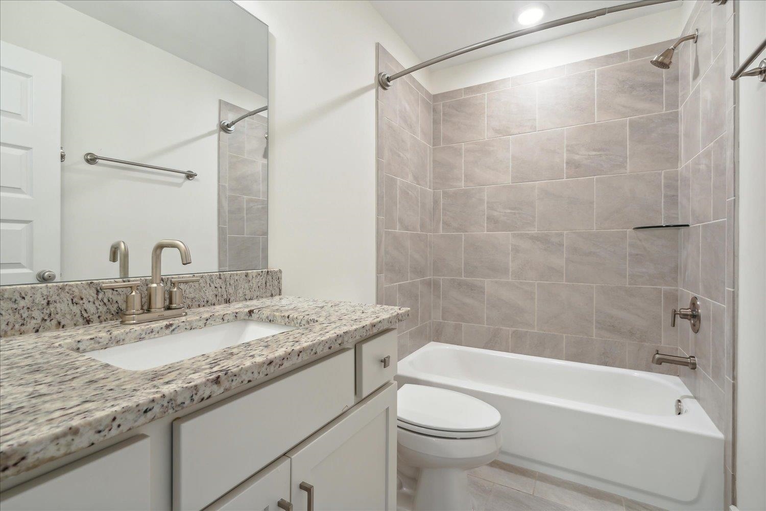 Full bathroom featuring tile patterned flooring, toilet, vanity, and tiled shower / bath