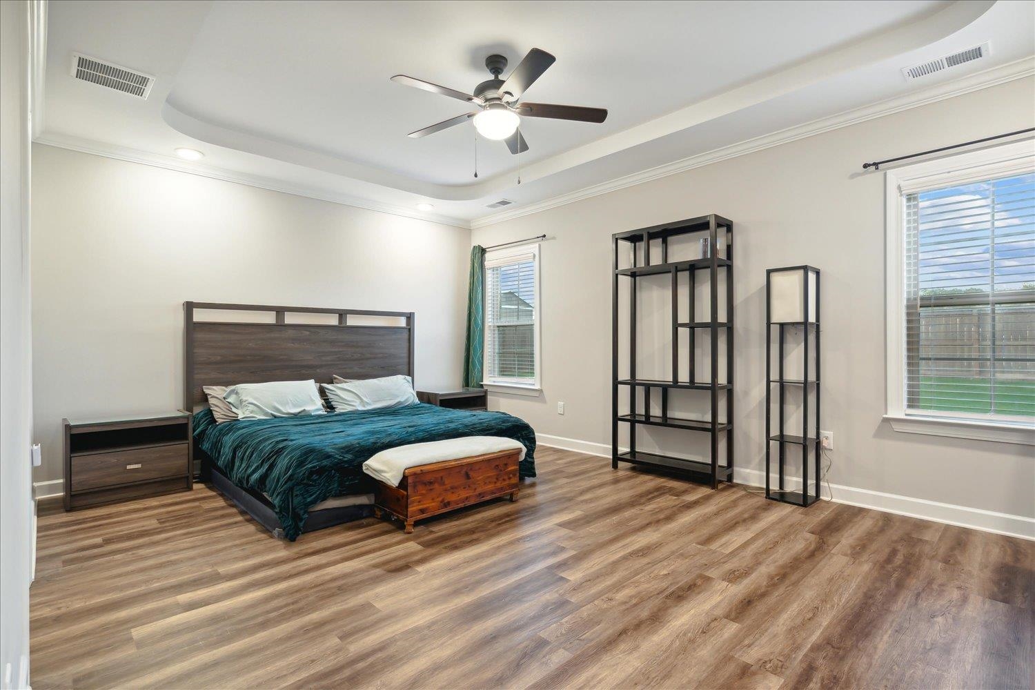 Bedroom with multiple windows, hardwood / wood-style floors, and a tray ceiling