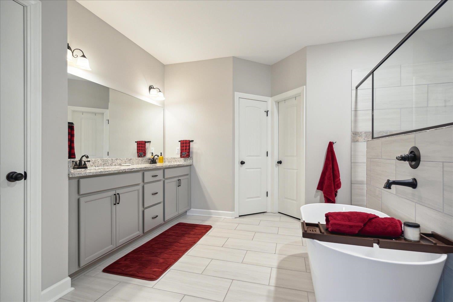 Bathroom featuring dual vanity, a bathtub, and tile patterned floors