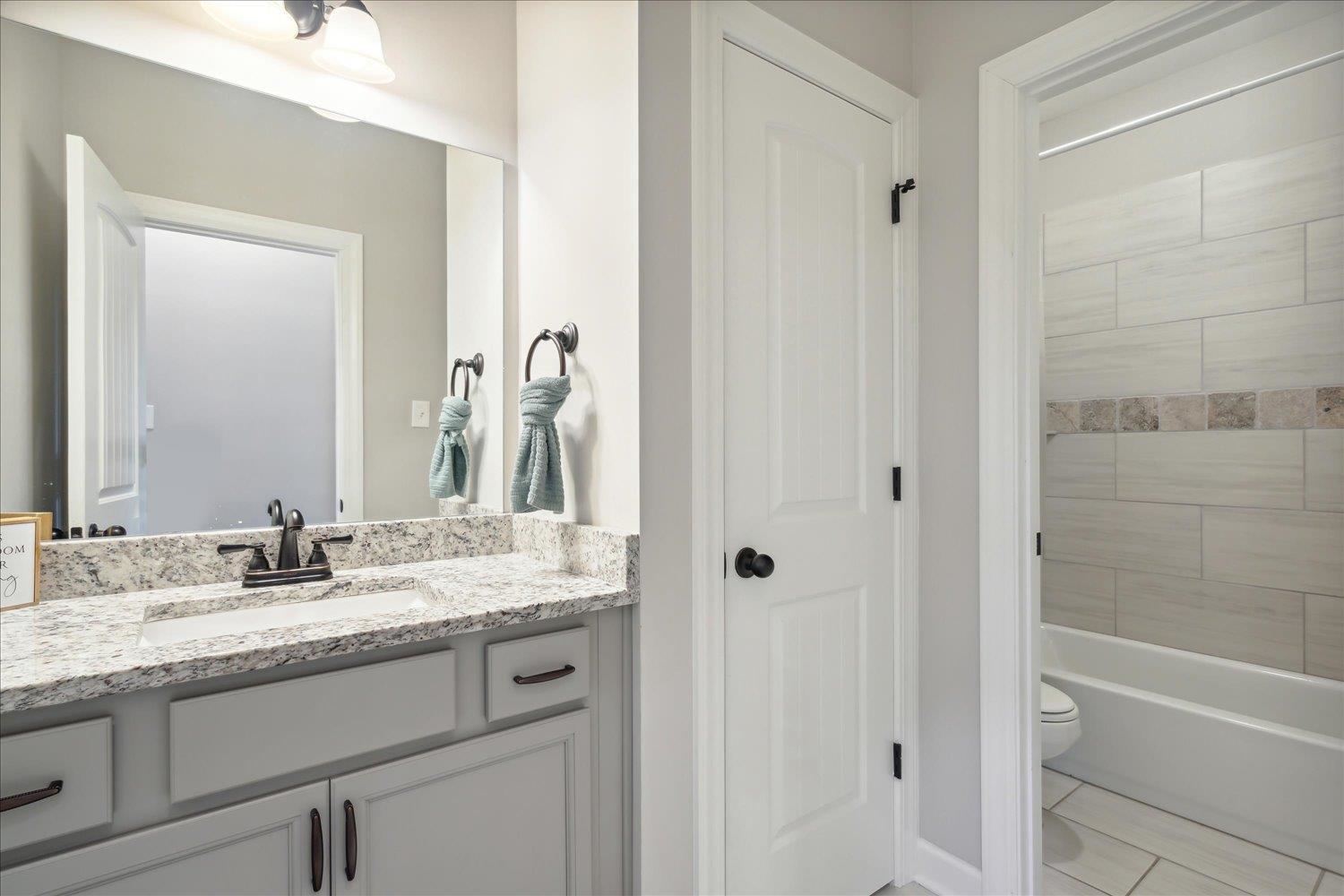 Full bathroom featuring vanity, tile patterned flooring, tiled shower / bath combo, and toilet