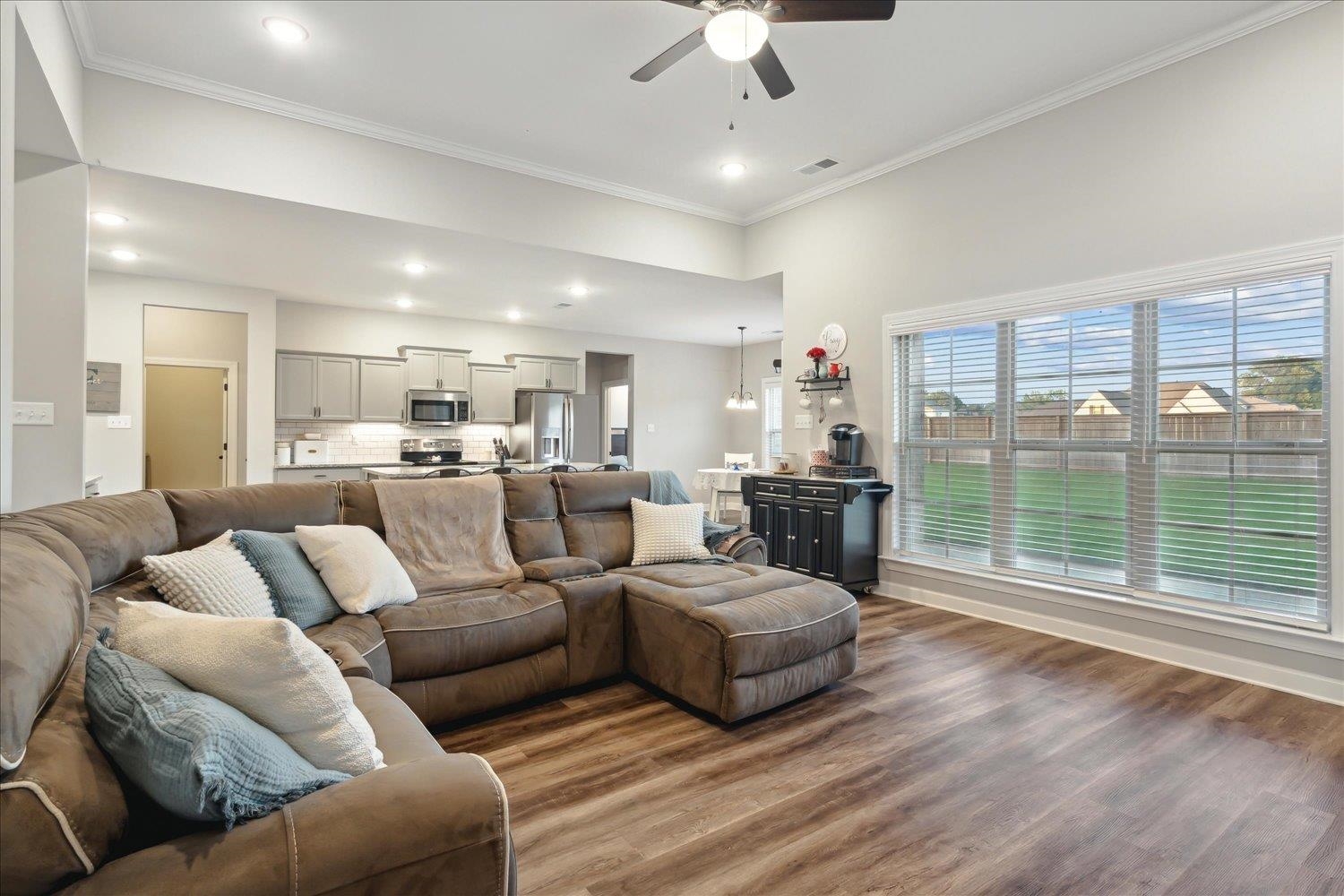 Living room with ornamental molding, wood-type flooring, and ceiling fan