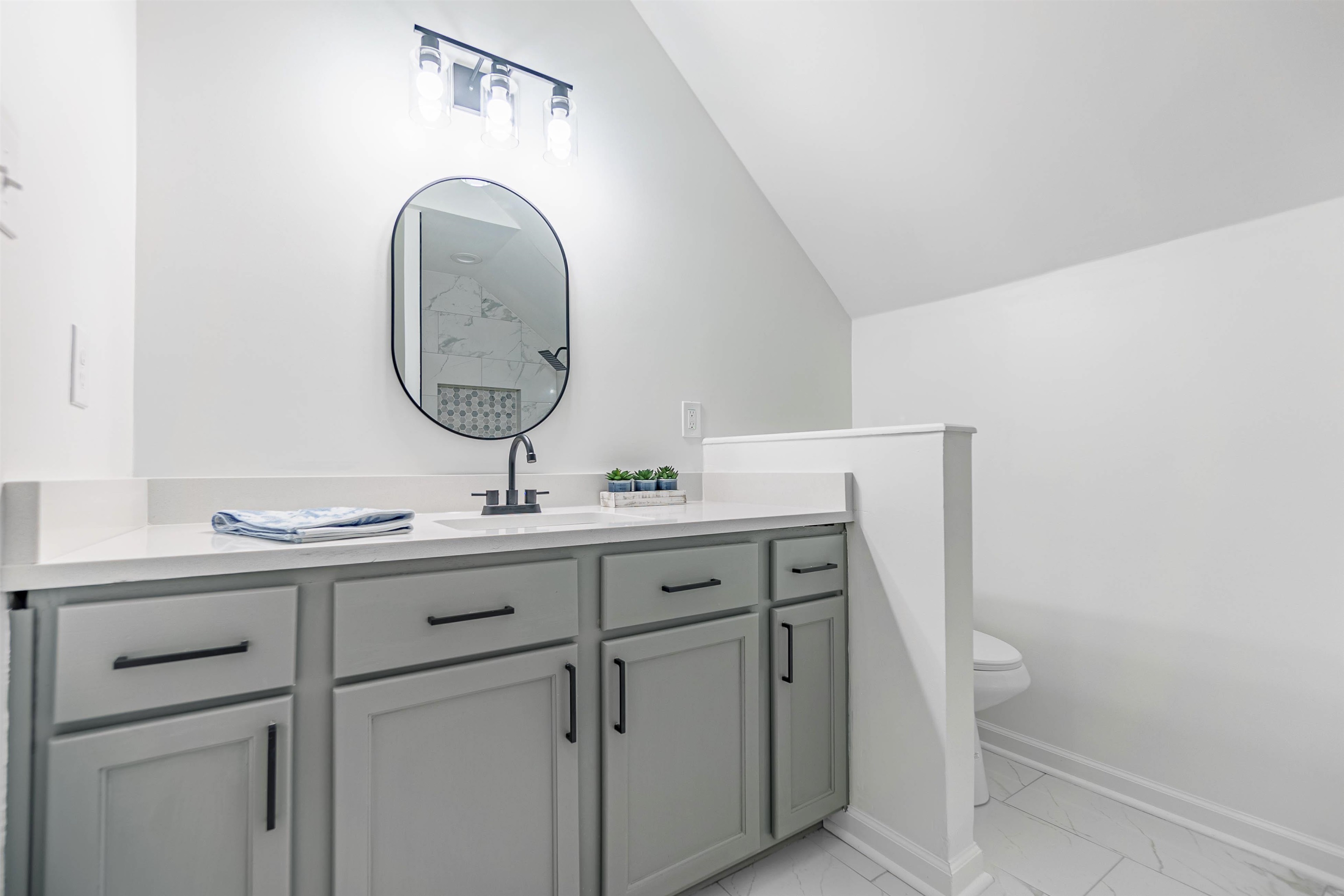 Bathroom with tile patterned floors, vanity, toilet, and vaulted ceiling