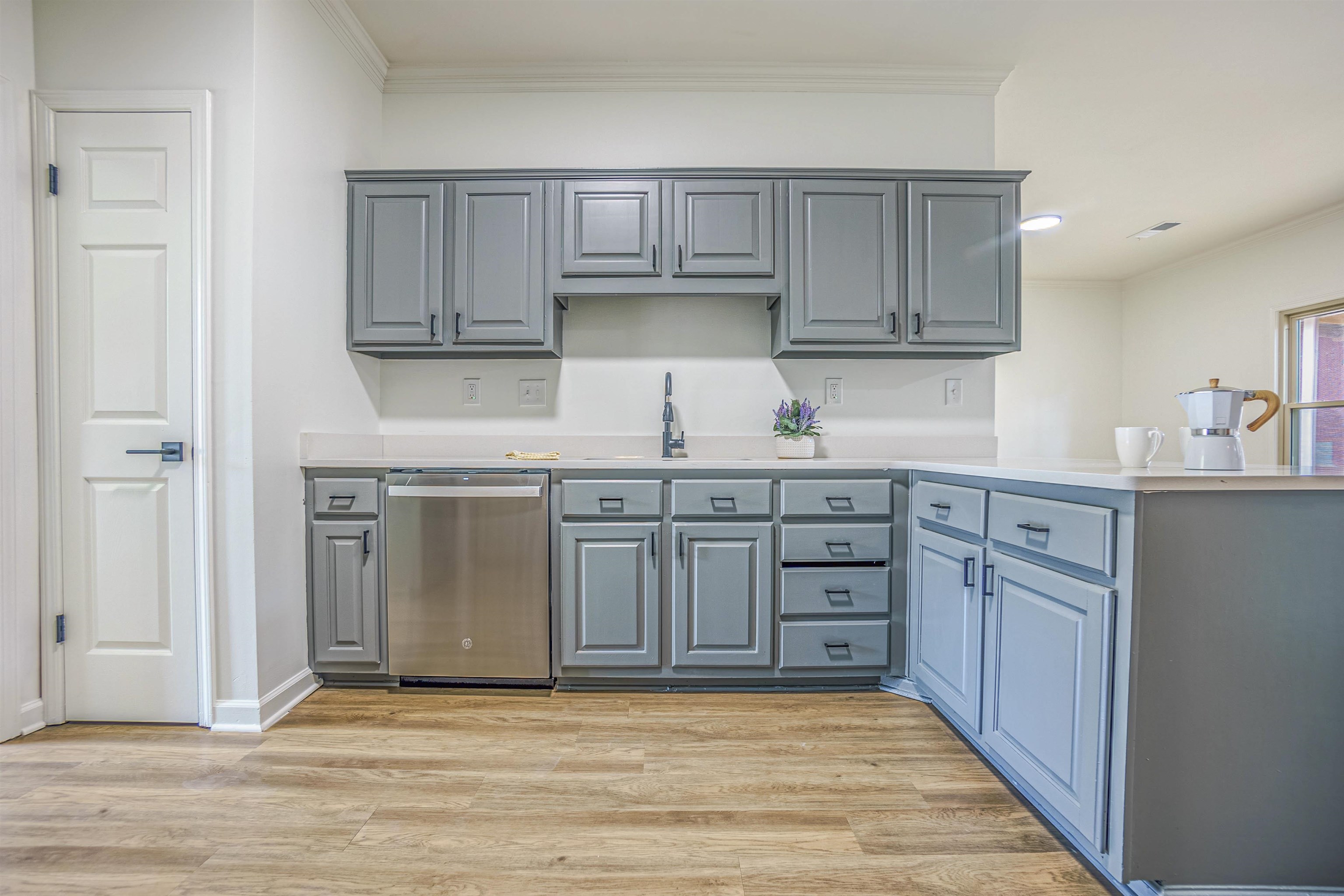 Kitchen featuring crown molding, light hardwood / wood-style flooring, dishwasher, sink, and gray cabinetry