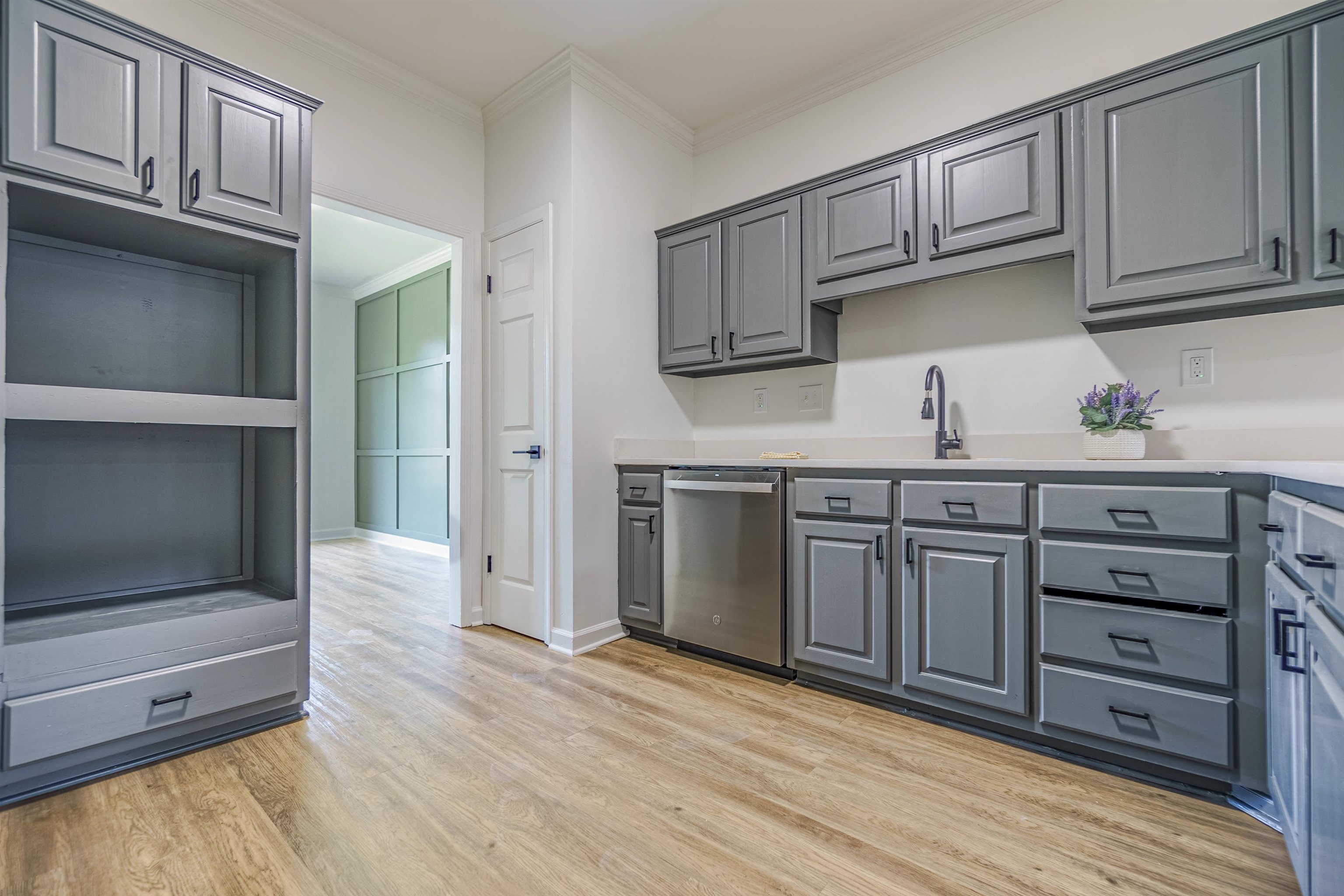 Kitchen with light hardwood / wood-style flooring, ornamental molding, dishwasher, sink, and gray cabinetry