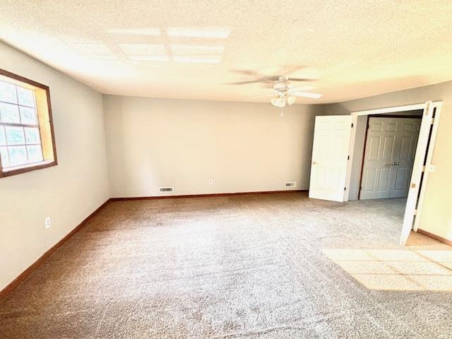 Unfurnished bedroom with a textured ceiling, ceiling fan, and light colored carpet