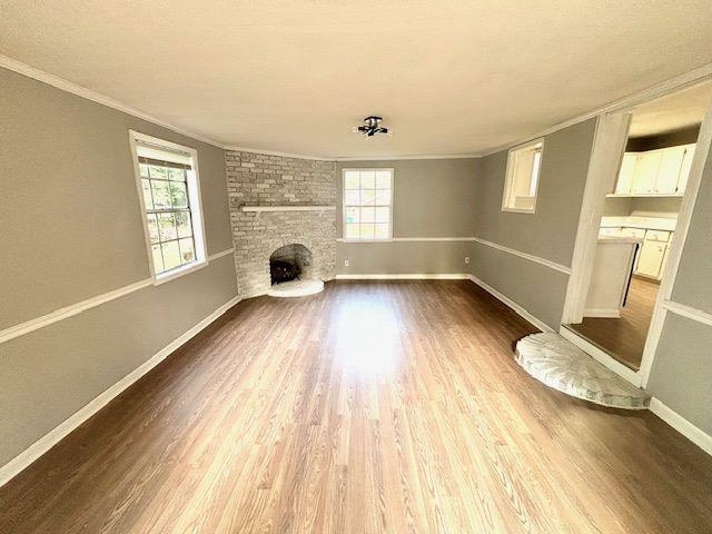 Unfurnished living room with a fireplace, wood-type flooring, and a healthy amount of sunlight
