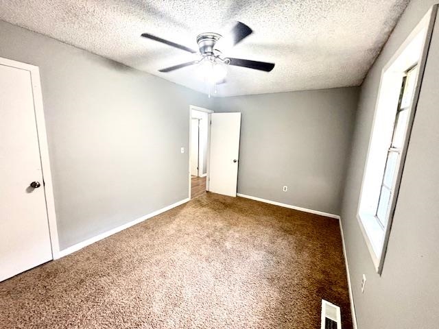 Unfurnished room featuring carpet floors, a textured ceiling, and ceiling fan