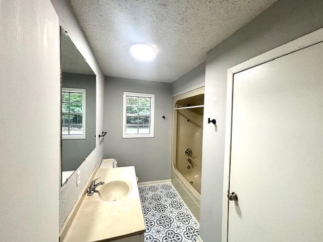 Bathroom featuring vanity, tile patterned floors, a textured ceiling, and shower / tub combination