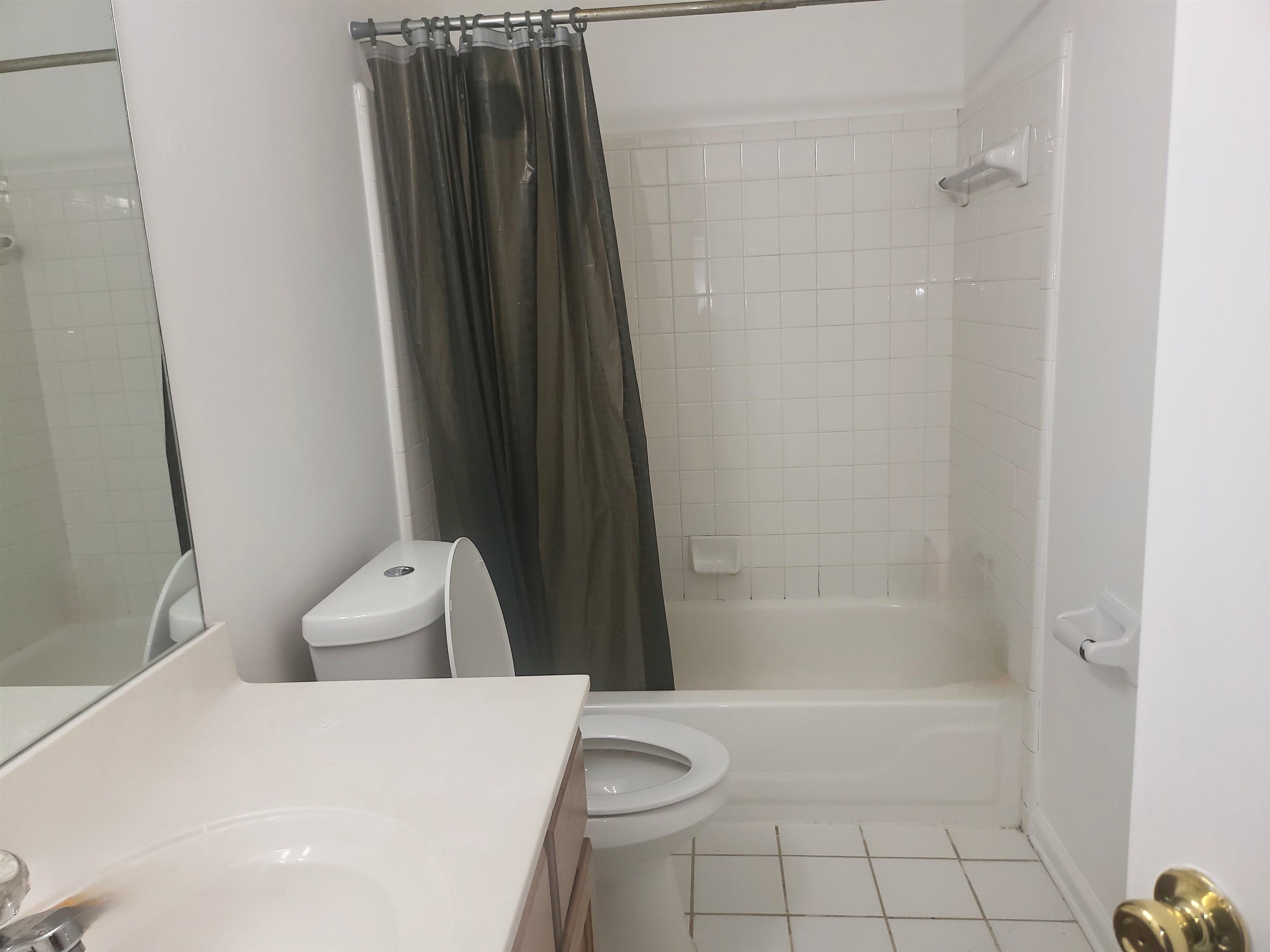 Full bathroom featuring vanity, shower / bathtub combination with curtain, toilet, and tile patterned floors