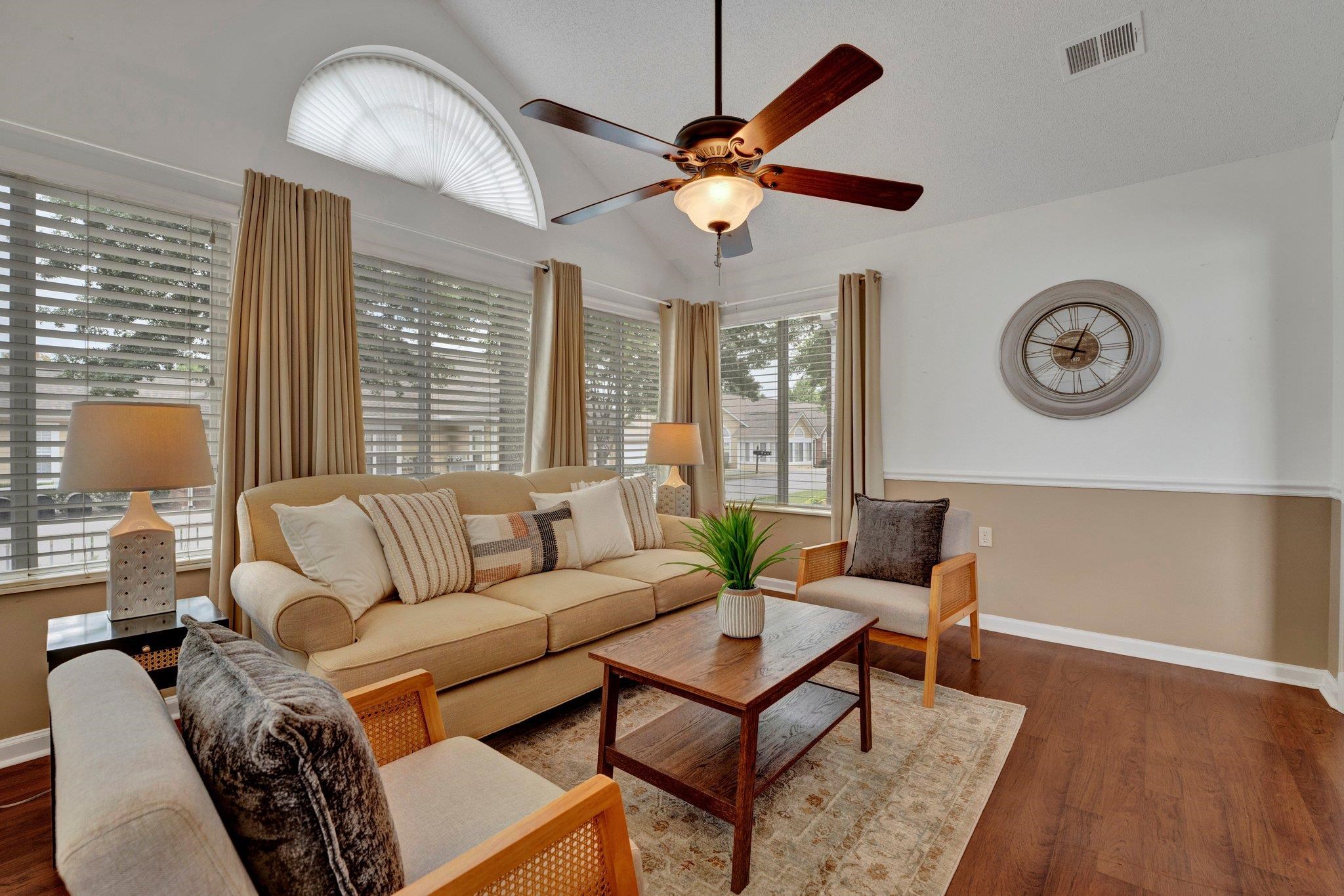 Living room with ceiling fan, dark wood-type flooring, and vaulted ceiling