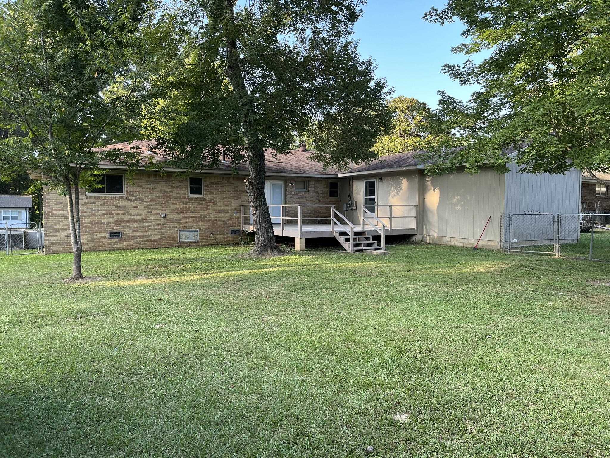 Back of property with a lawn and a wooden deck