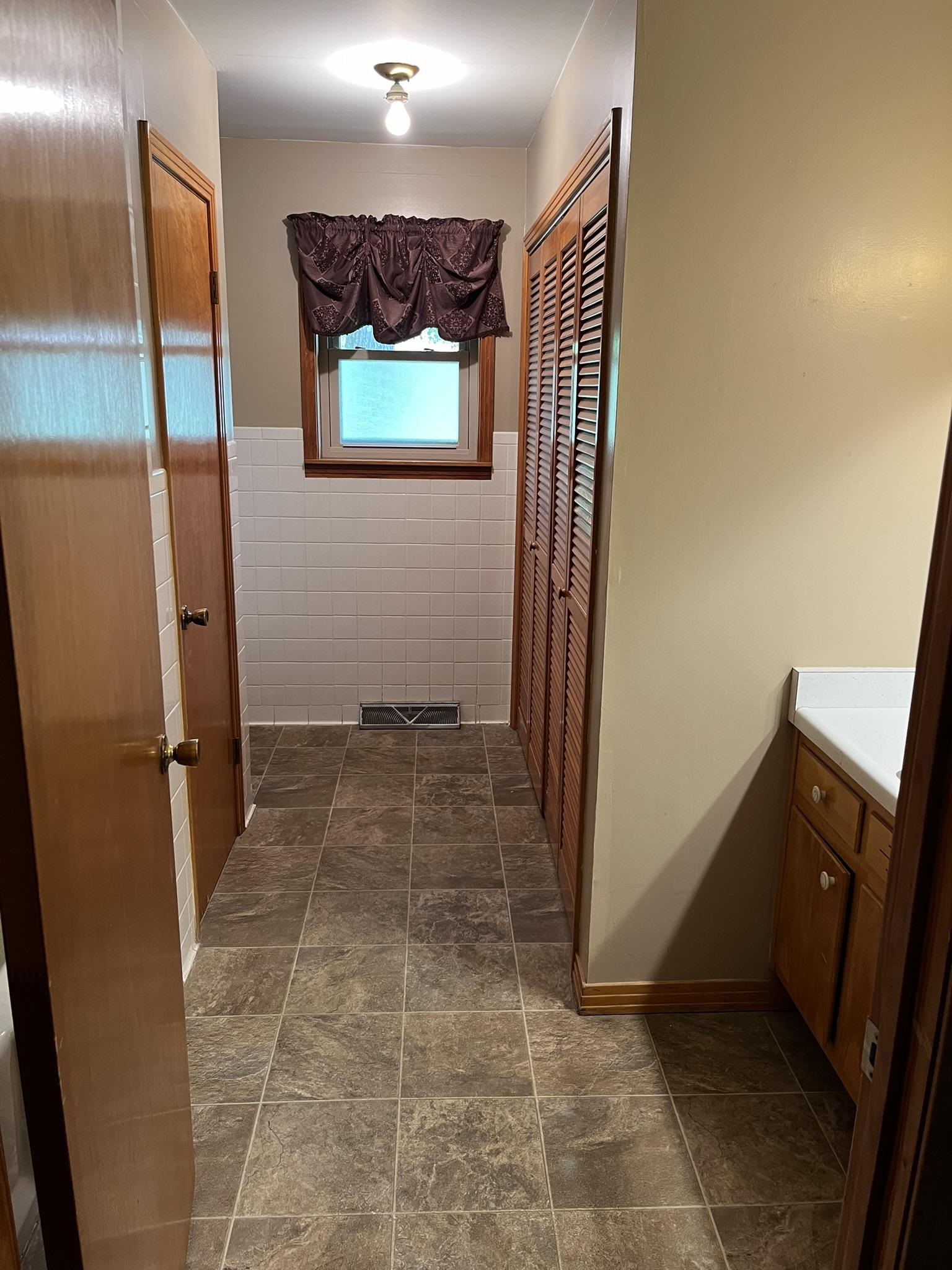 Corridor with tile walls and dark tile patterned flooring