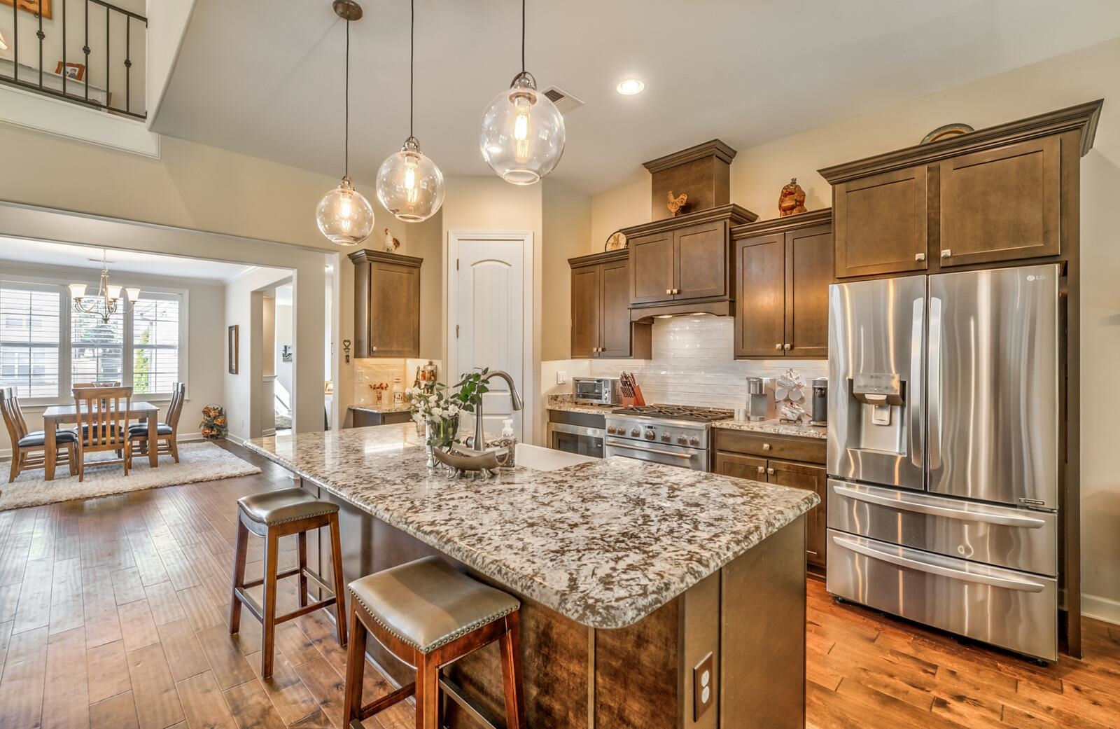 Kitchen with appliances with stainless steel finishes, pendant lighting, backsplash, an island with sink, and hardwood / wood-style flooring