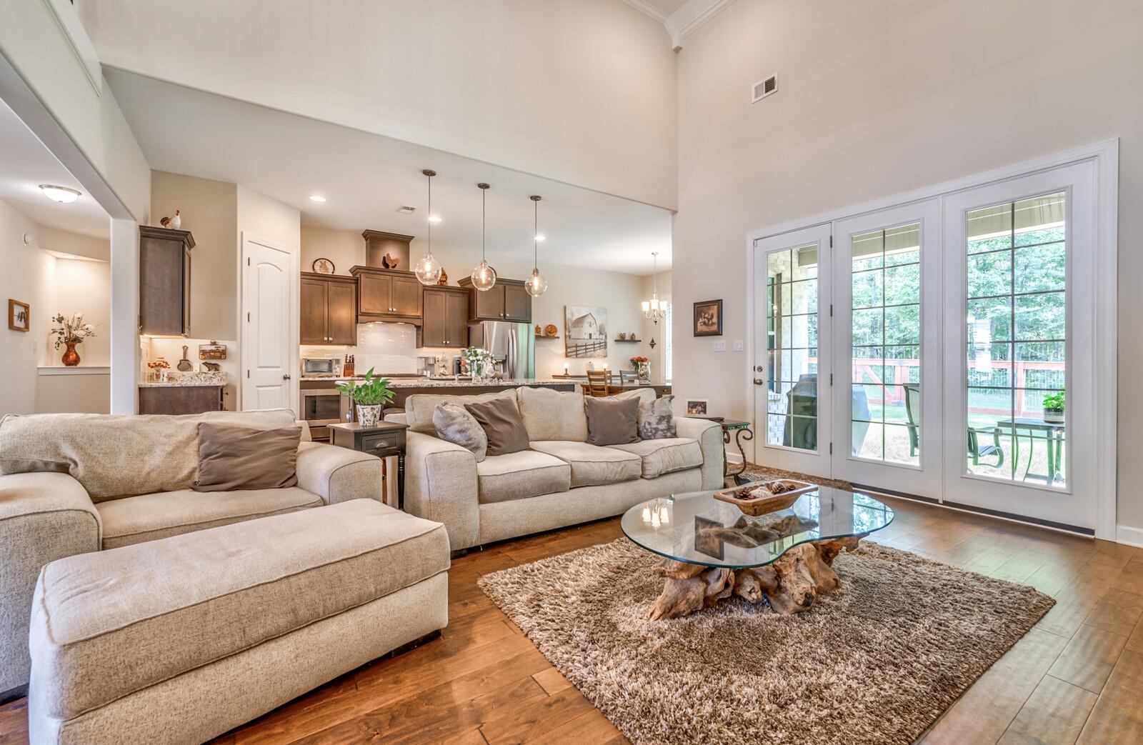 Living room featuring an inviting chandelier, wood-type flooring, and a high ceiling