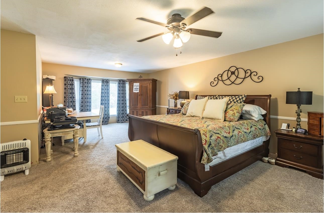 Carpeted bedroom featuring ceiling fan