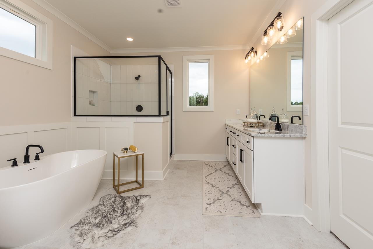 Bathroom with double sink vanity, tile patterned floors, crown molding, and independent shower and bath