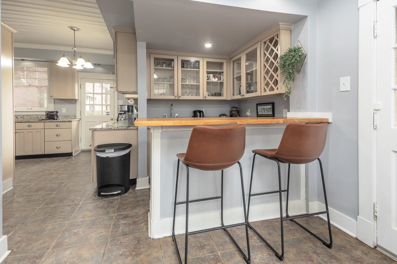 Kitchen with kitchen peninsula, decorative light fixtures, crown molding, and butcher block counters