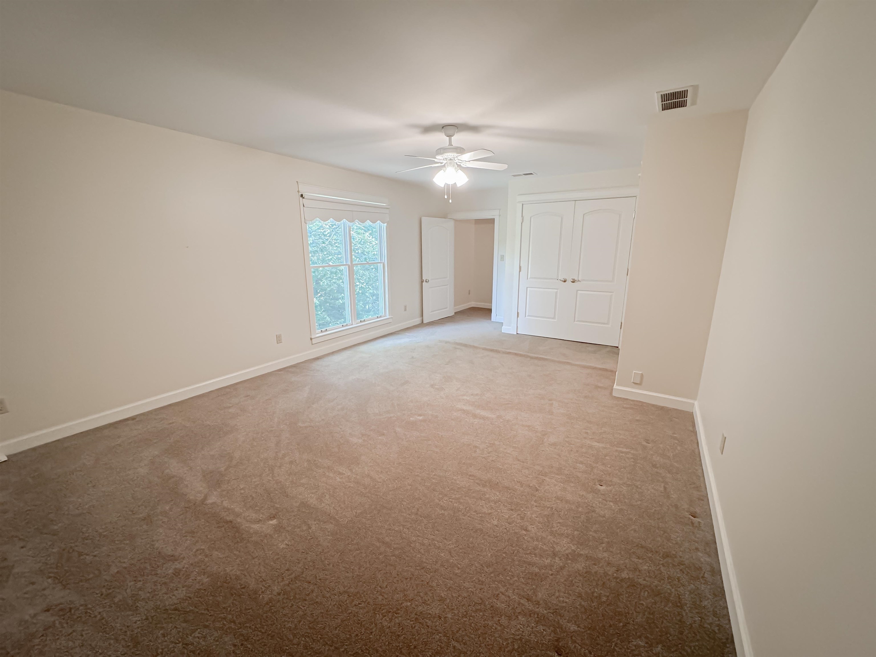 Unfurnished bedroom featuring ceiling fan and light colored carpet