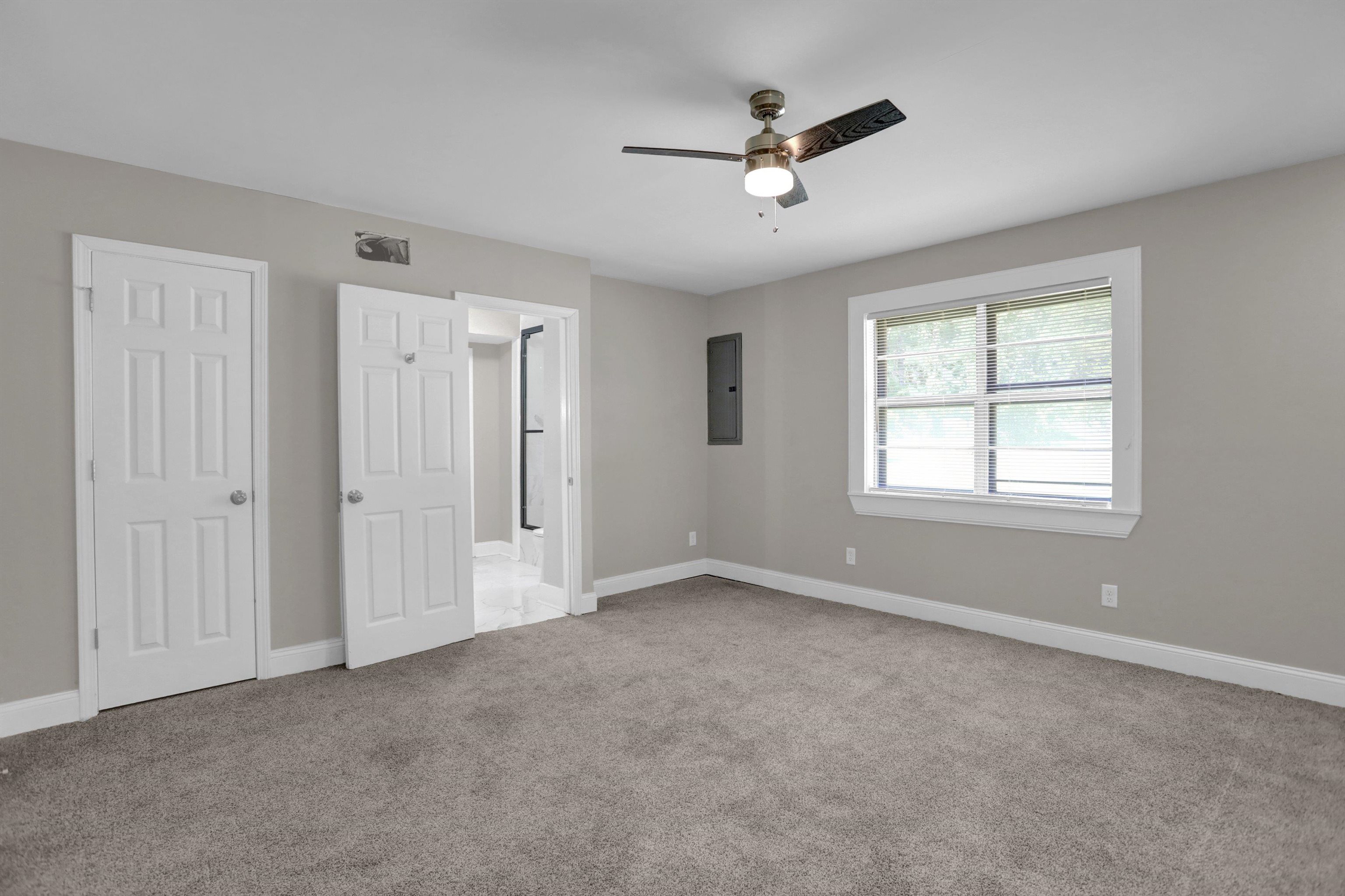 Unfurnished bedroom featuring ceiling fan, light carpet, and electric panel