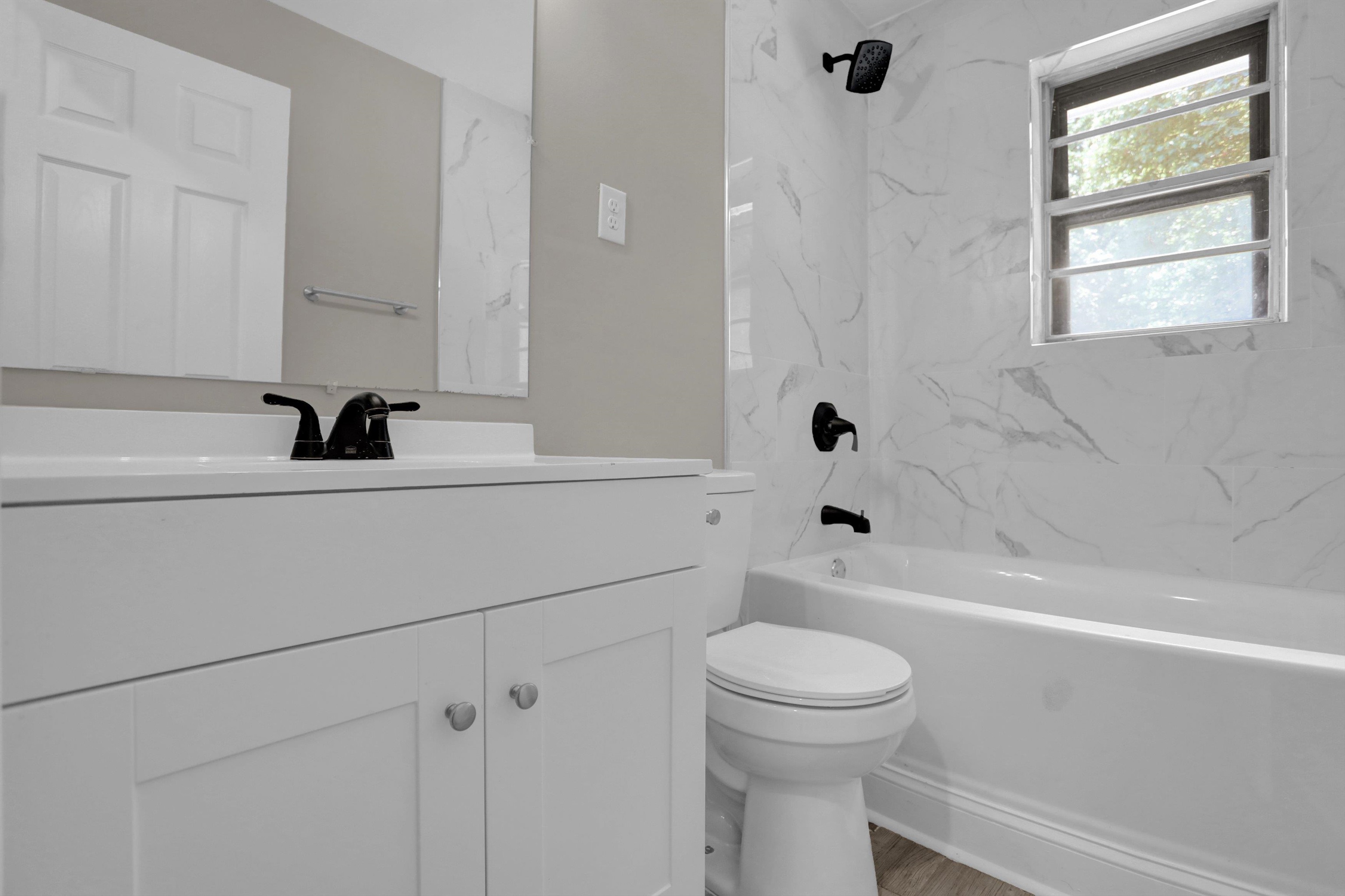 Full bathroom featuring hardwood / wood-style flooring, tiled shower / bath, vanity, and toilet