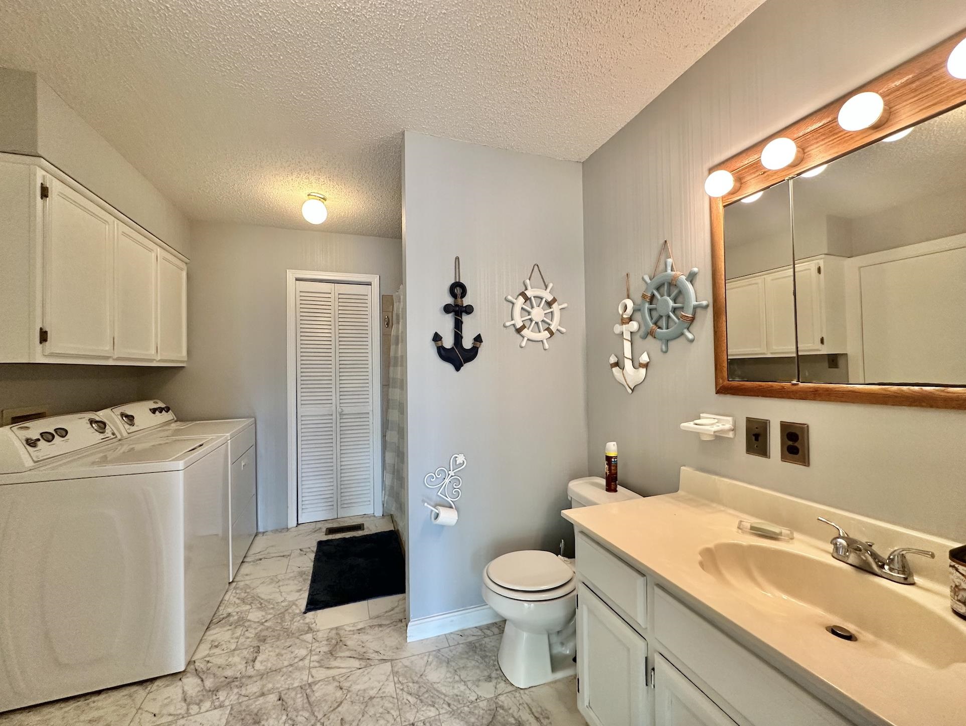 Bathroom featuring separate washer and dryer, toilet, tile patterned flooring, vanity, and a textured ceiling