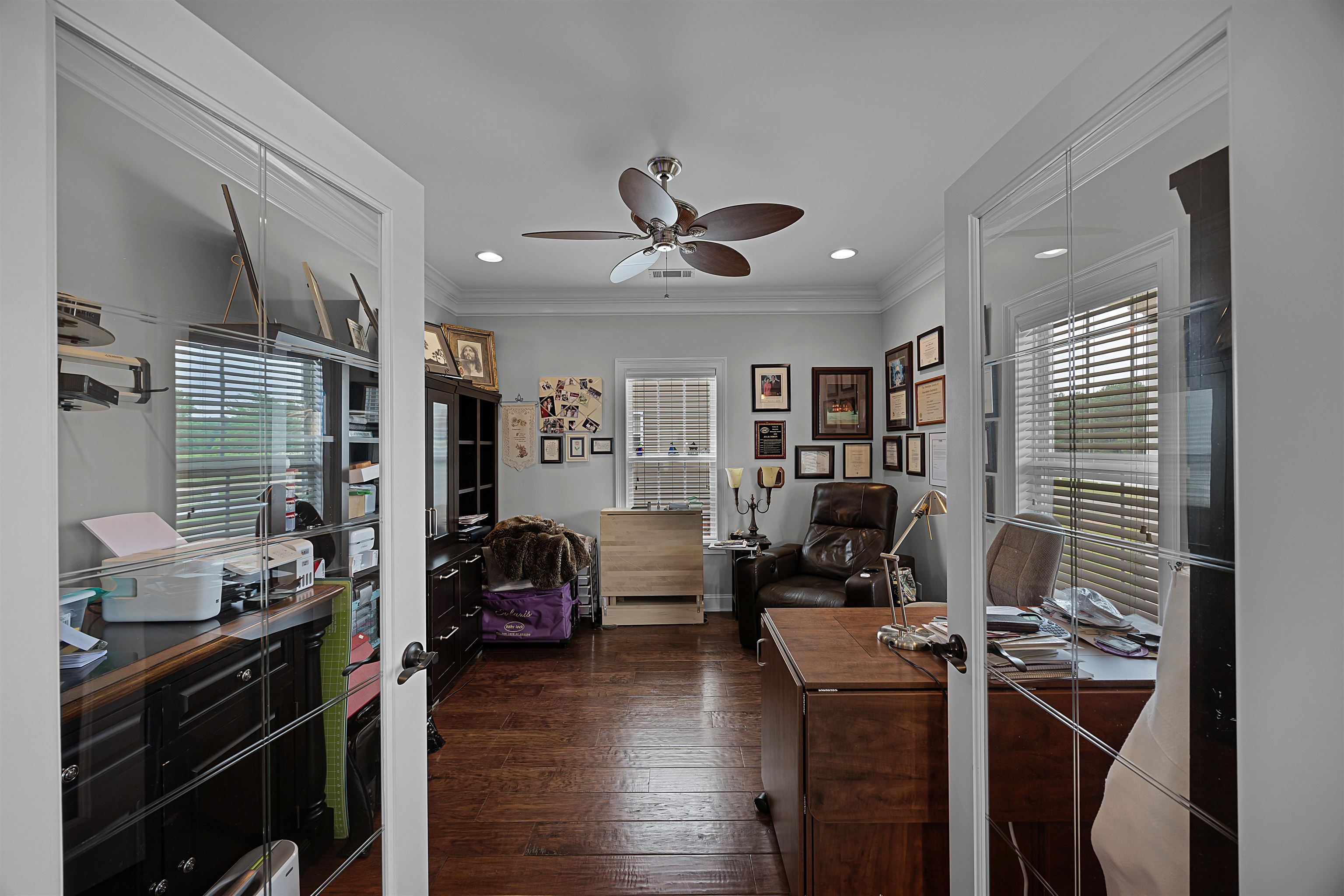 Office featuring dark wood-type flooring, ornamental molding, a wealth of natural light, and ceiling fan