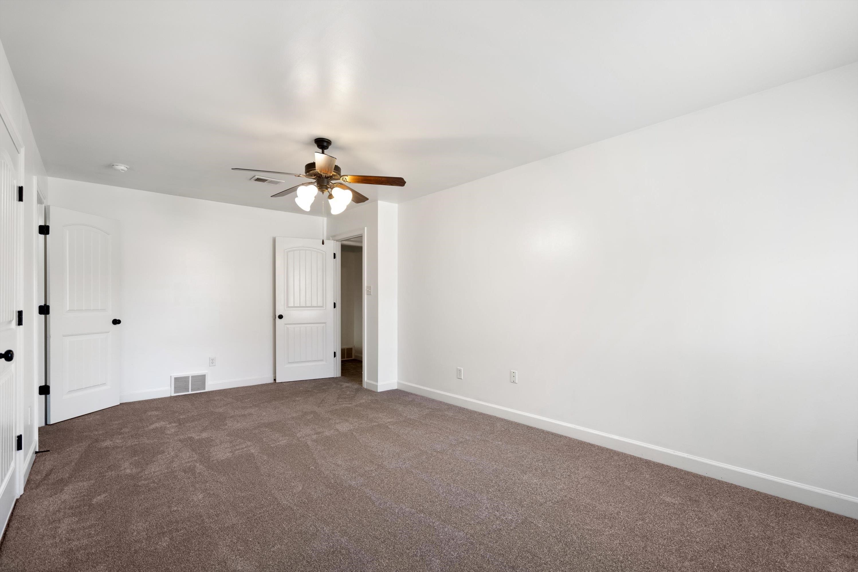 Unfurnished bedroom with ceiling fan and carpet