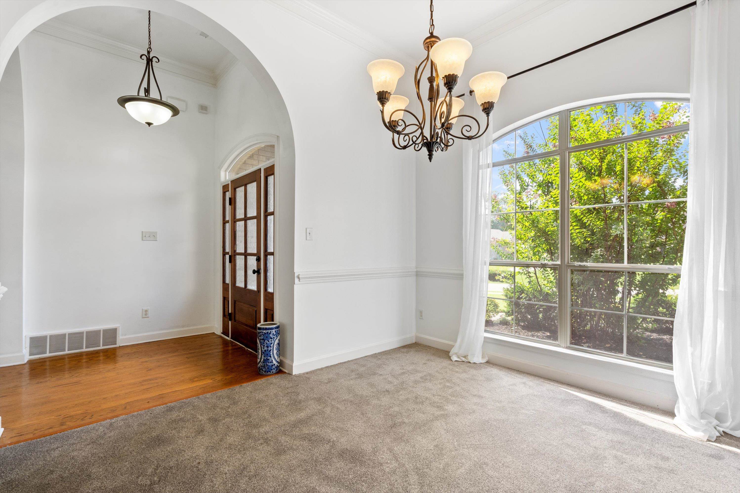 Empty room featuring a chandelier, ornamental molding, and carpet flooring