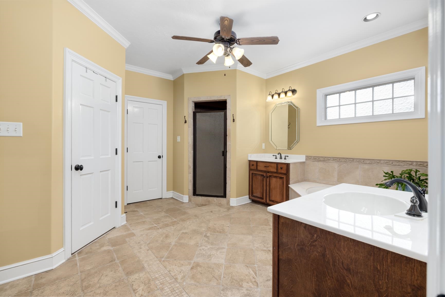 Bathroom featuring tile patterned floors, a shower with shower door, vanity, ceiling fan, and crown molding