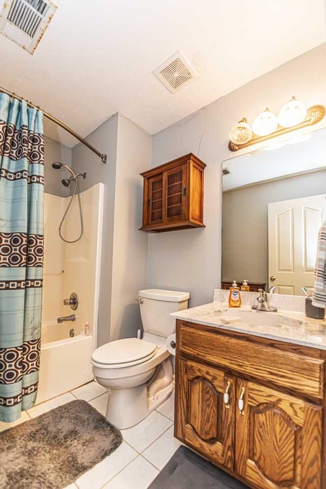 Full bathroom featuring tile patterned floors, vanity, shower / tub combo, and toilet