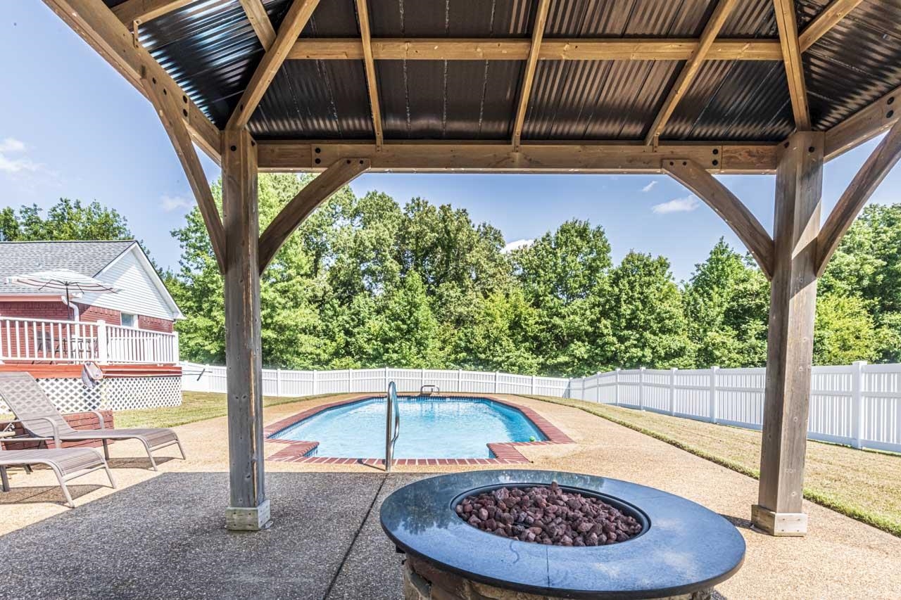 View of pool featuring a patio area, a gazebo, a wooden deck, and a fire pit