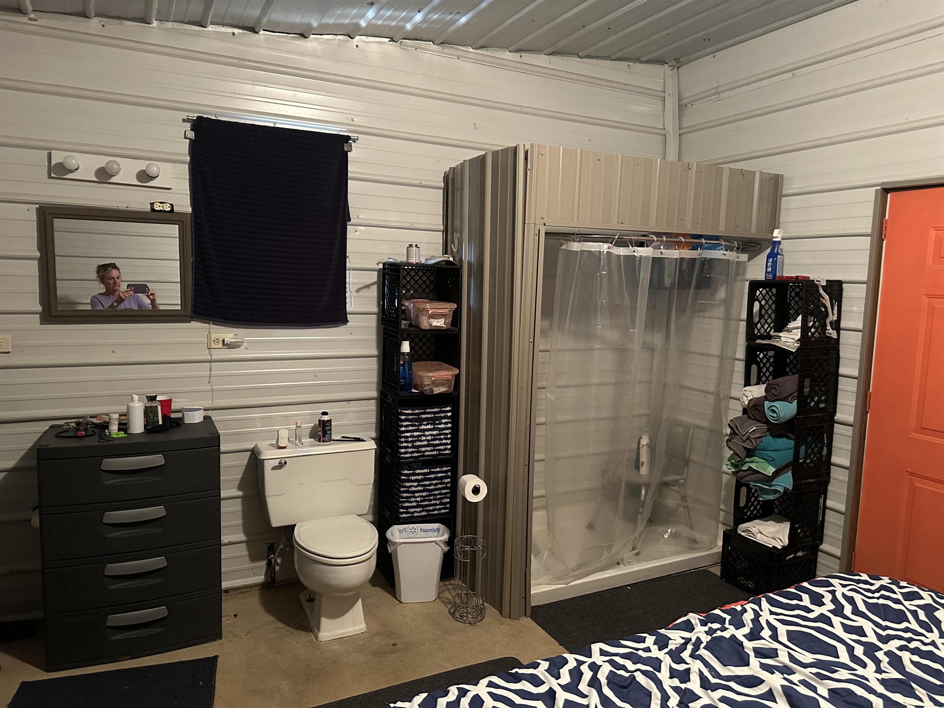 Bathroom featuring wooden walls, toilet, and walk in shower