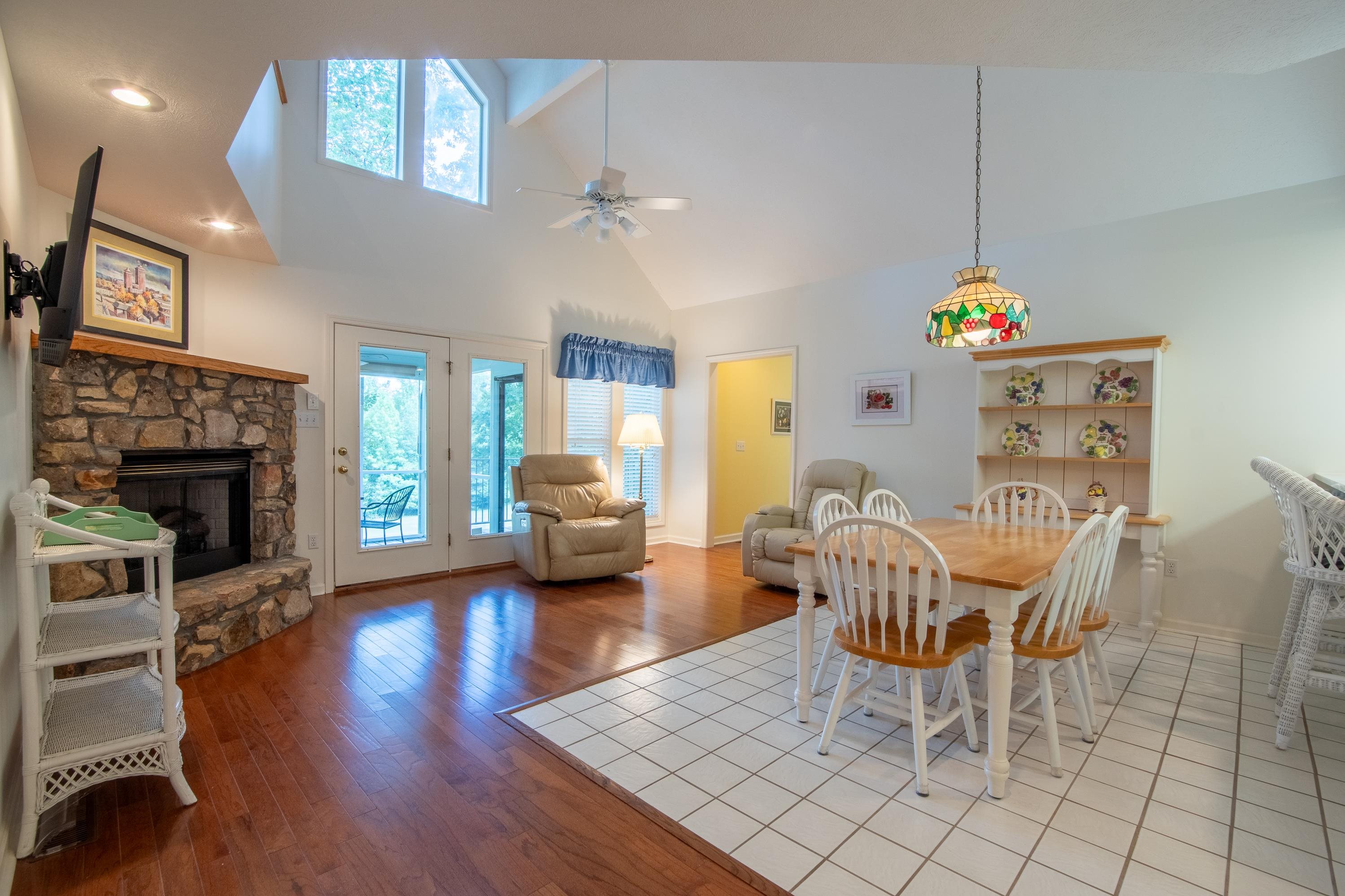 Dining area with a fireplace, high vaulted ceiling, ceiling fan, and light wood-type flooring