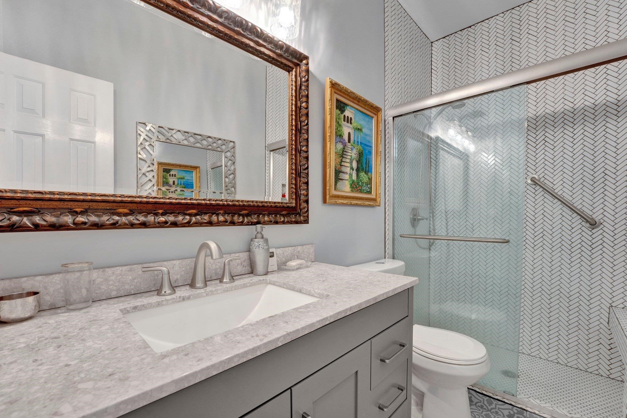 Bathroom featuring a shower with shower door, vanity, and toilet